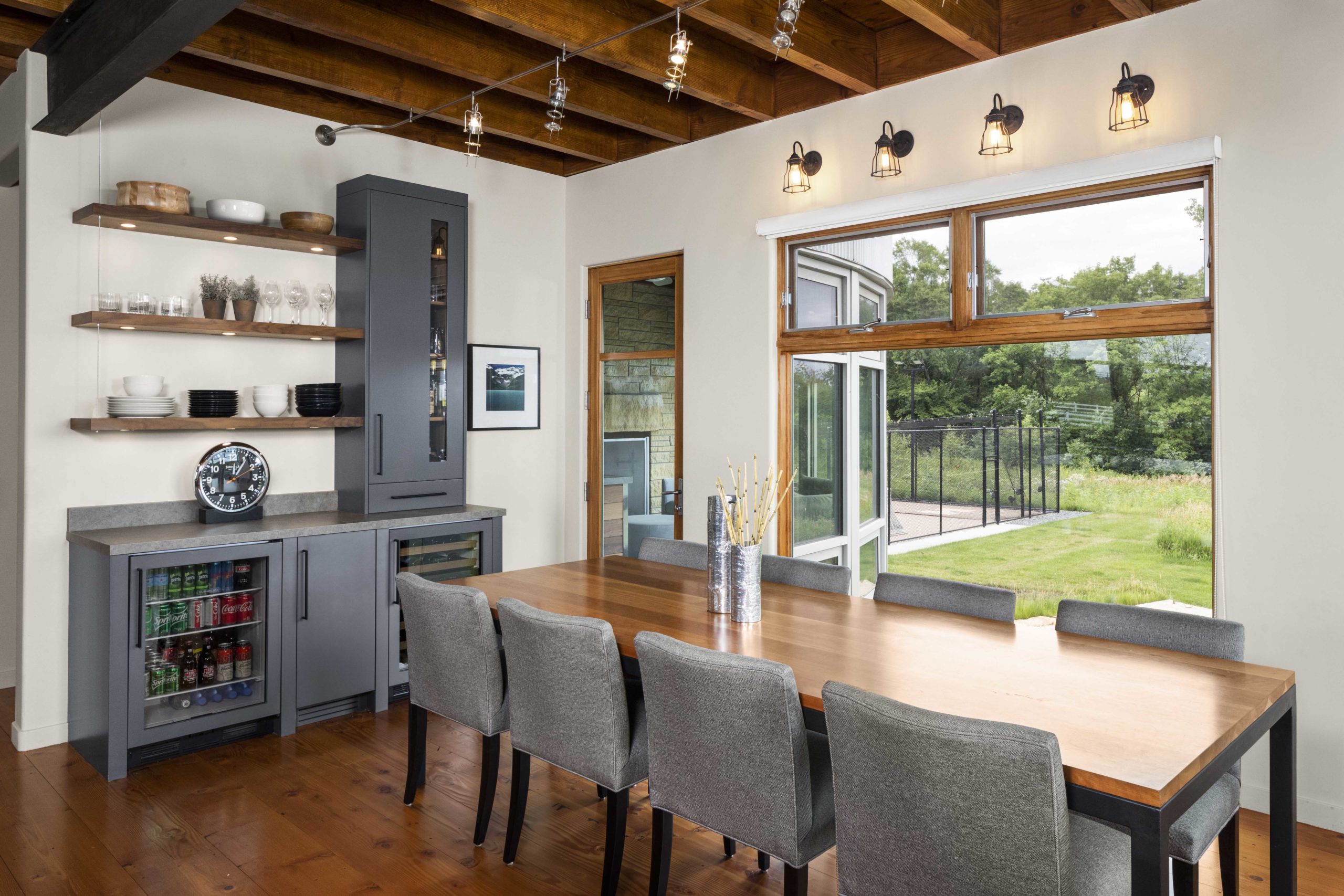 A dining room with a contemporary wooden table and farmhouse chairs.