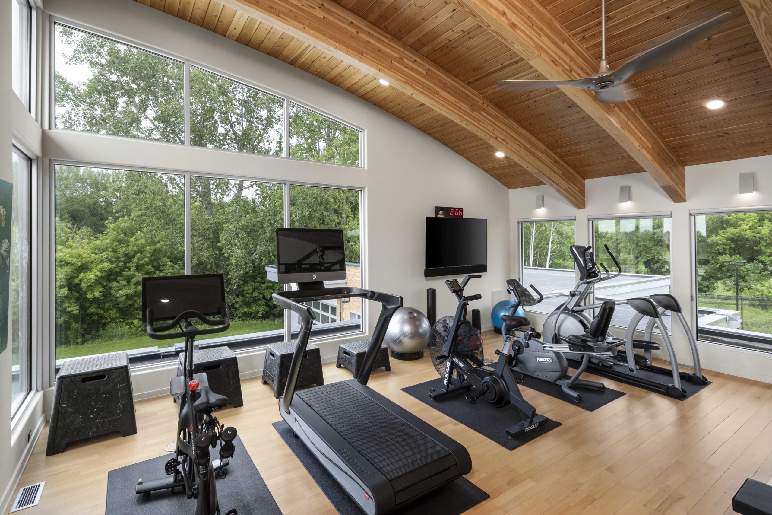 A contemporary gym room with exercise equipment and a large window.