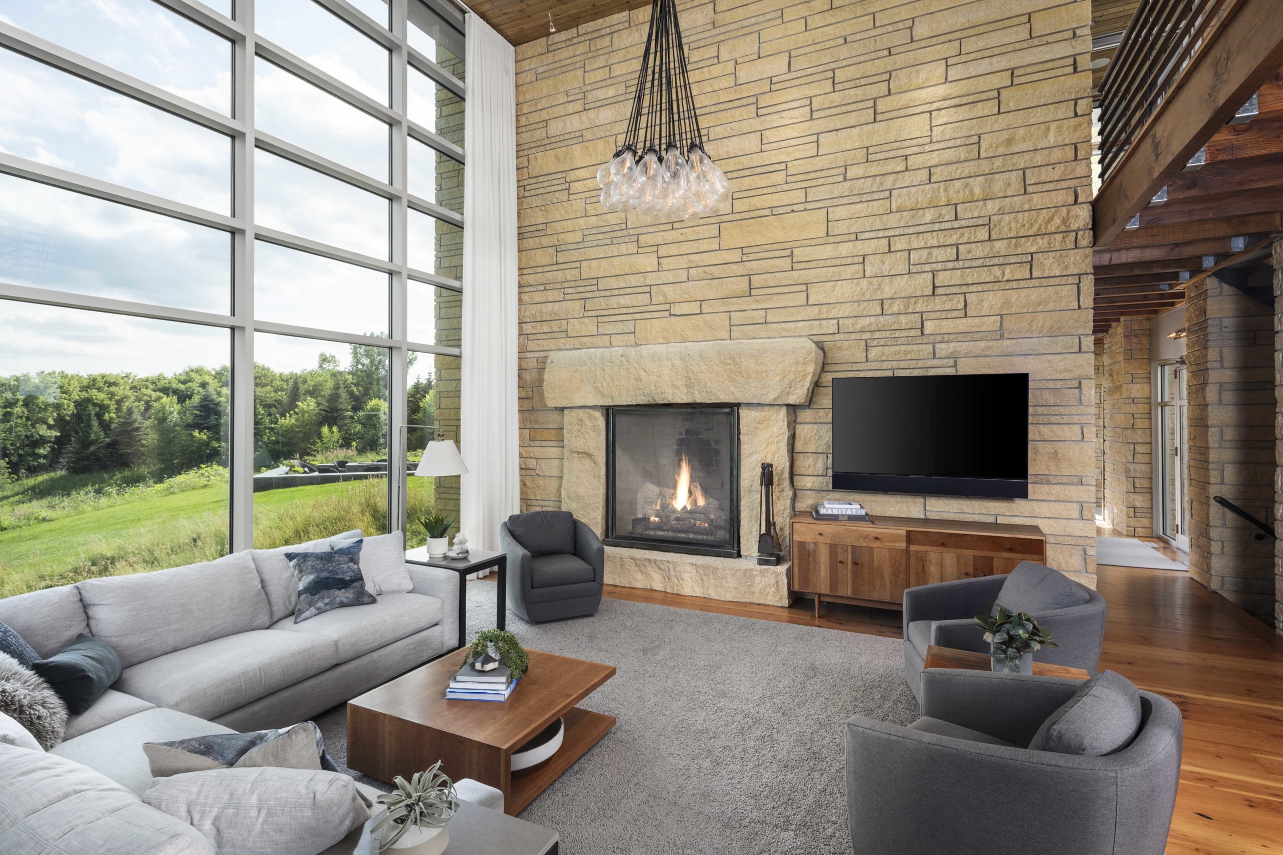 A contemporary living room with large windows and a fireplace.
