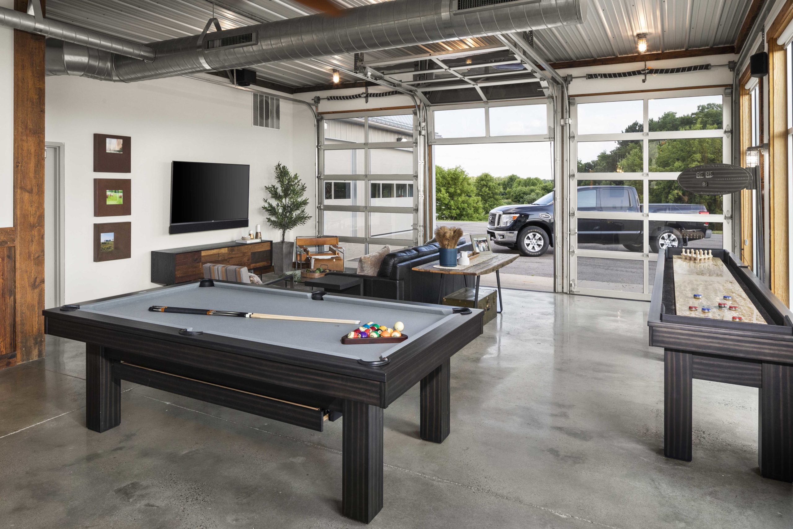 A contemporary game room with a pool table and foosball table in a farmhouse setting.