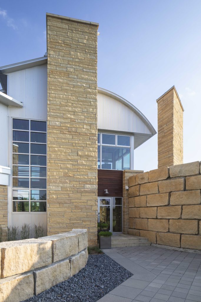 The entrance to a contemporary building featuring a stone wall.