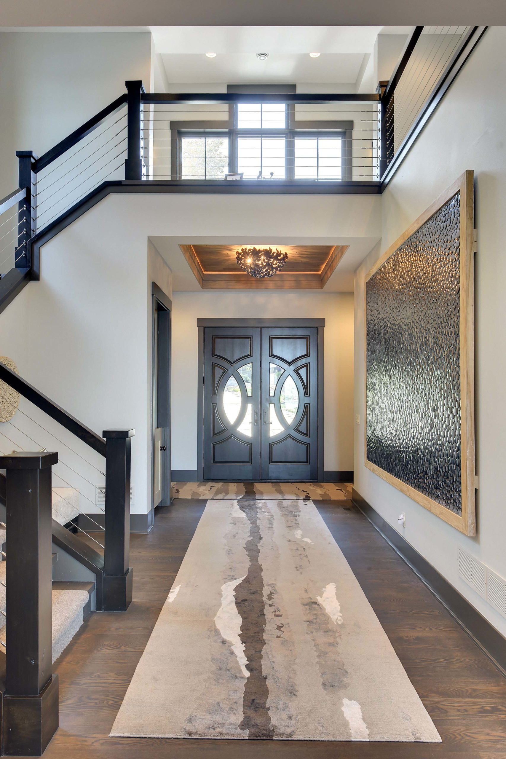 A modern entryway with a staircase and a rug.