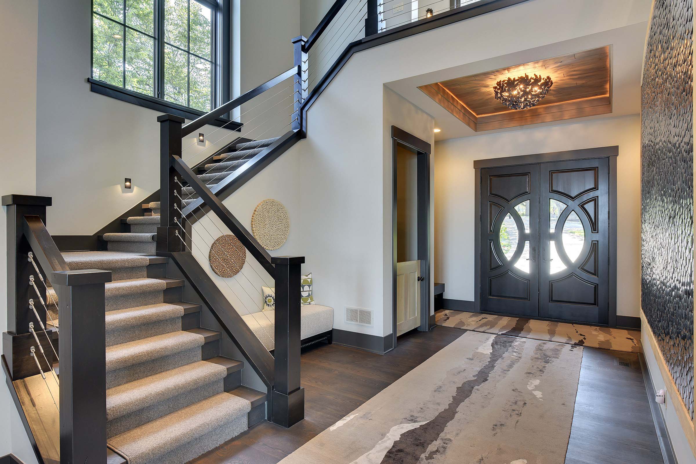 An entryway with a staircase and a rug.