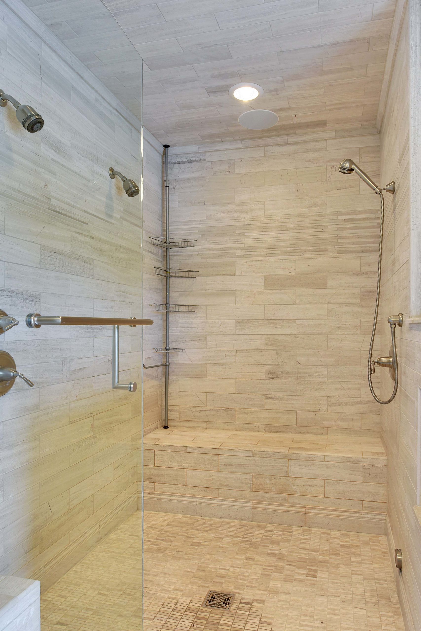 A contemporary bathroom with a glass shower and a bench.