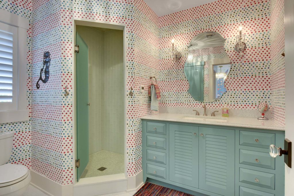 A contemporary bathroom with polka dot wallpaper and blue cabinets.