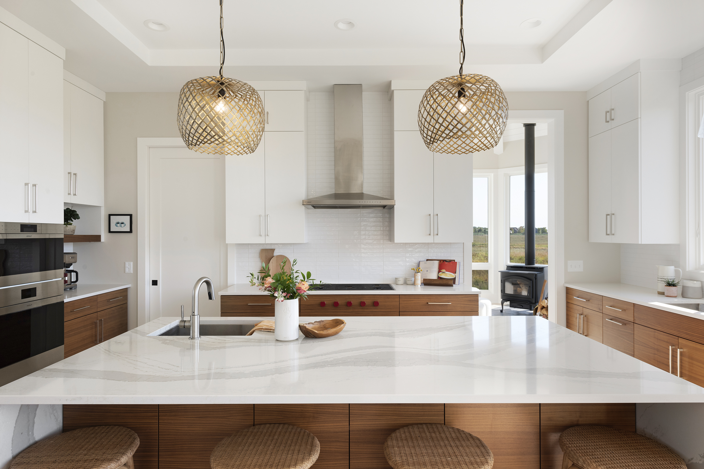 A prairie transitional custom home with a modern kitchen featuring a marble island and stools.