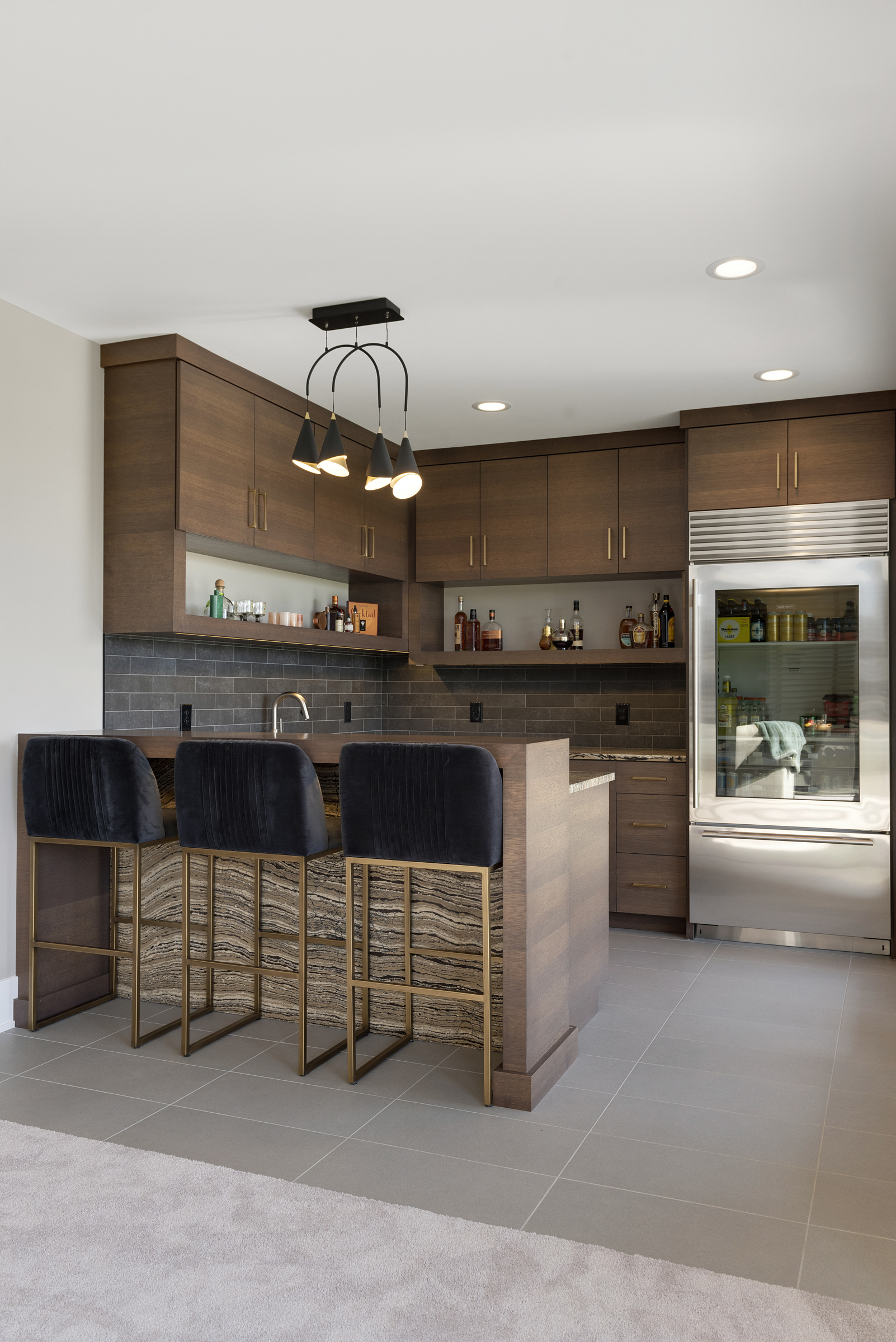 A prairie transitional custom home kitchen with stainless steel appliances and bar stools.