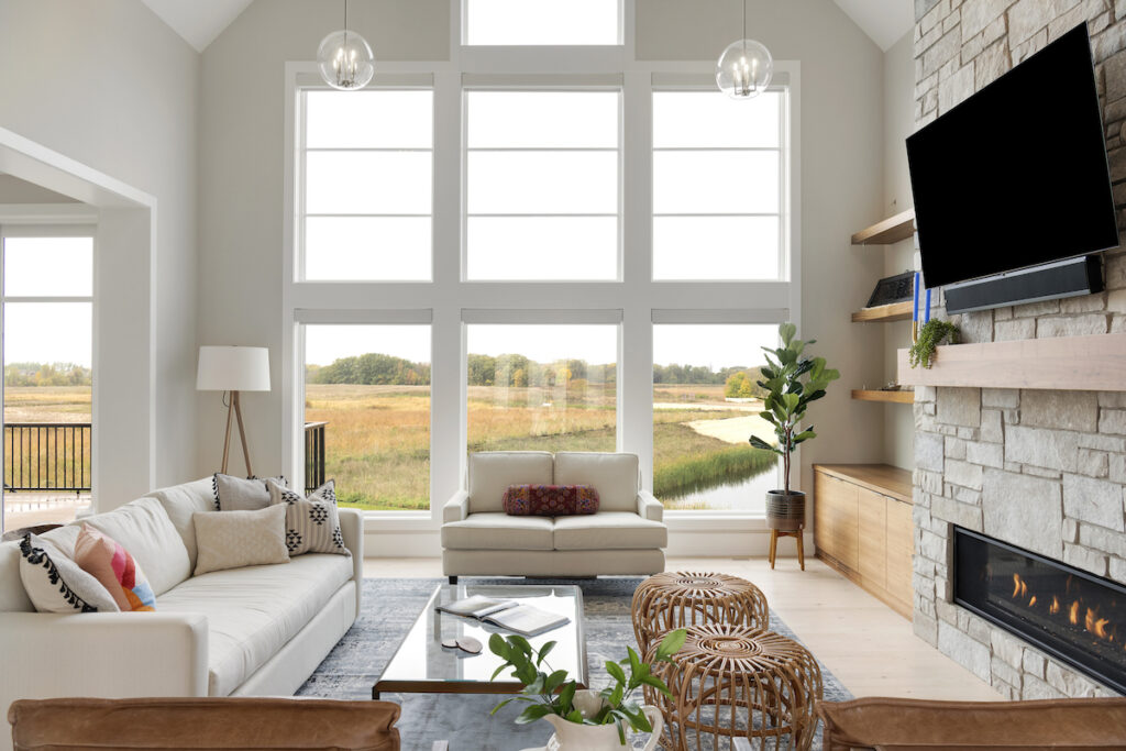 A prairie transitional living room with large windows and a fireplace in a custom home.