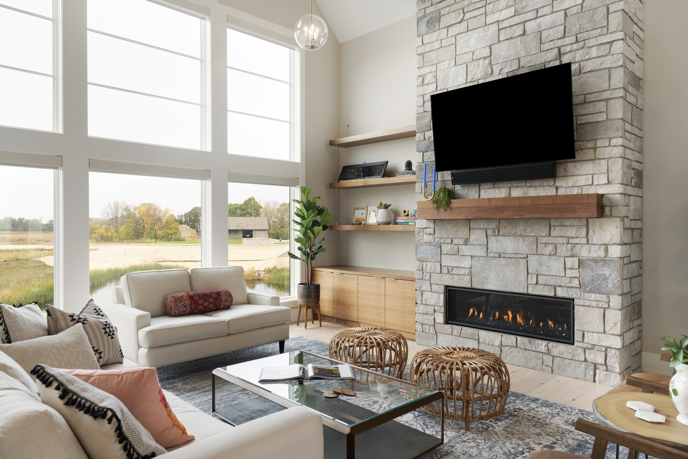 A prairie transitional living room with a stone fireplace and large windows.