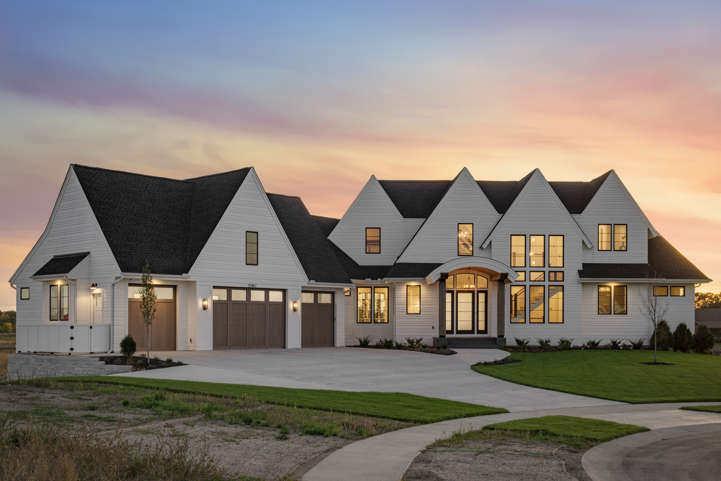 The exterior of a large white prairie home at dusk.