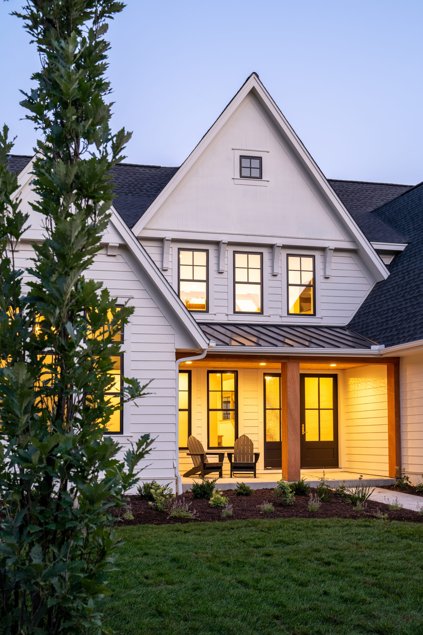 The exterior of a white home at dusk, featuring The Lake Escape custom home remodel.