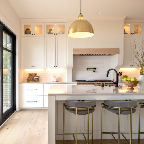 The Lake Escape custom home remodel features a white kitchen with a center island and stools.