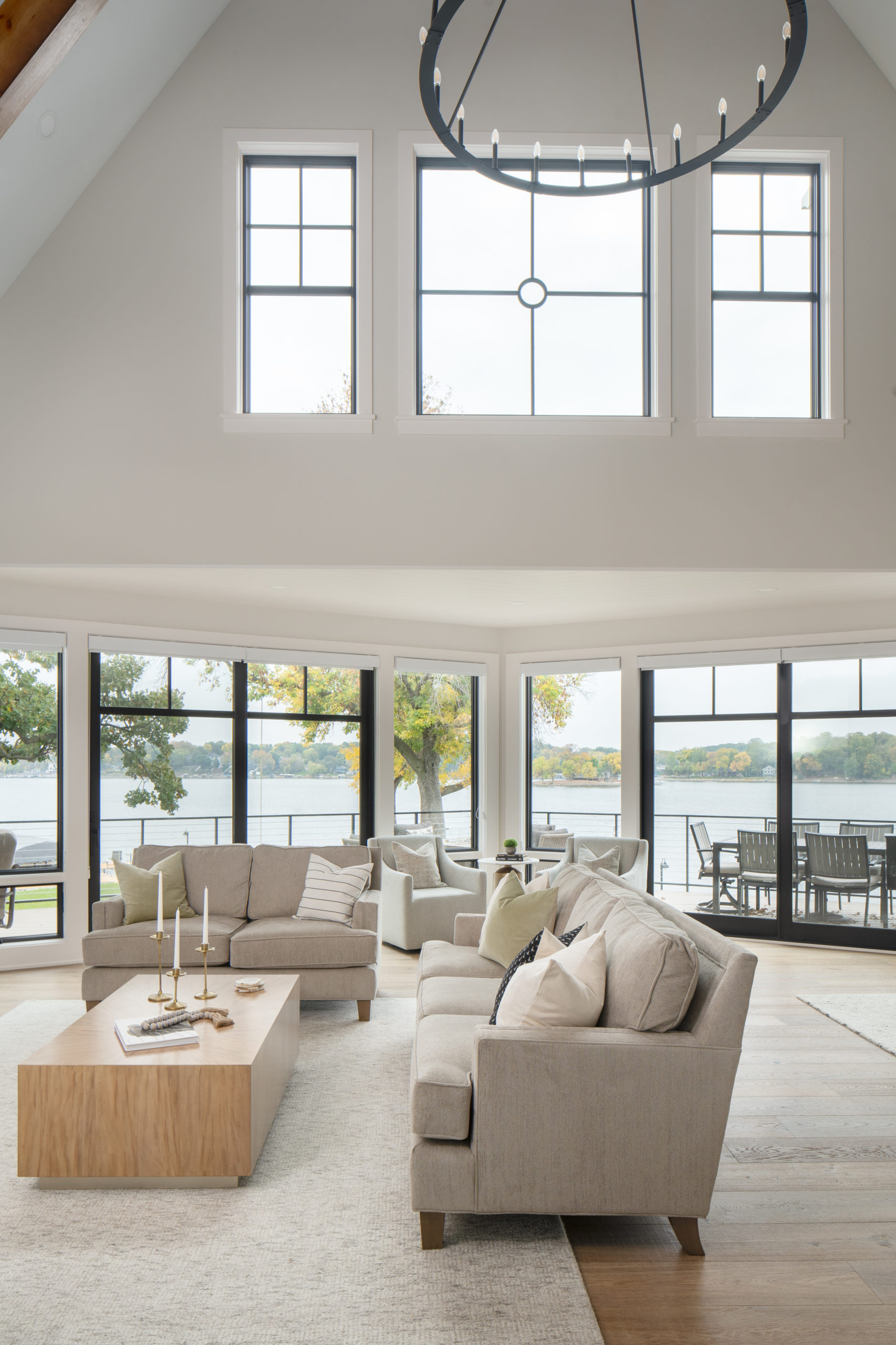 The Lake Escape custom home remodel transformed a large living room with large windows overlooking the lake.