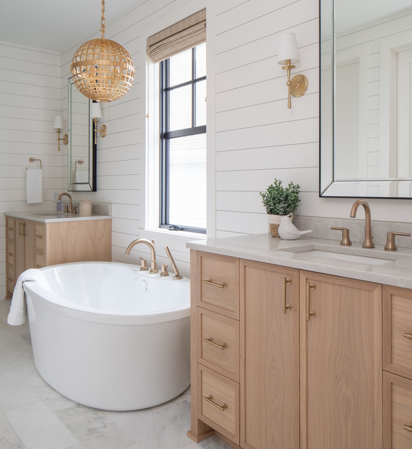 The Lake Escape custom home remodel features a white bathroom with wooden cabinets and a large tub.