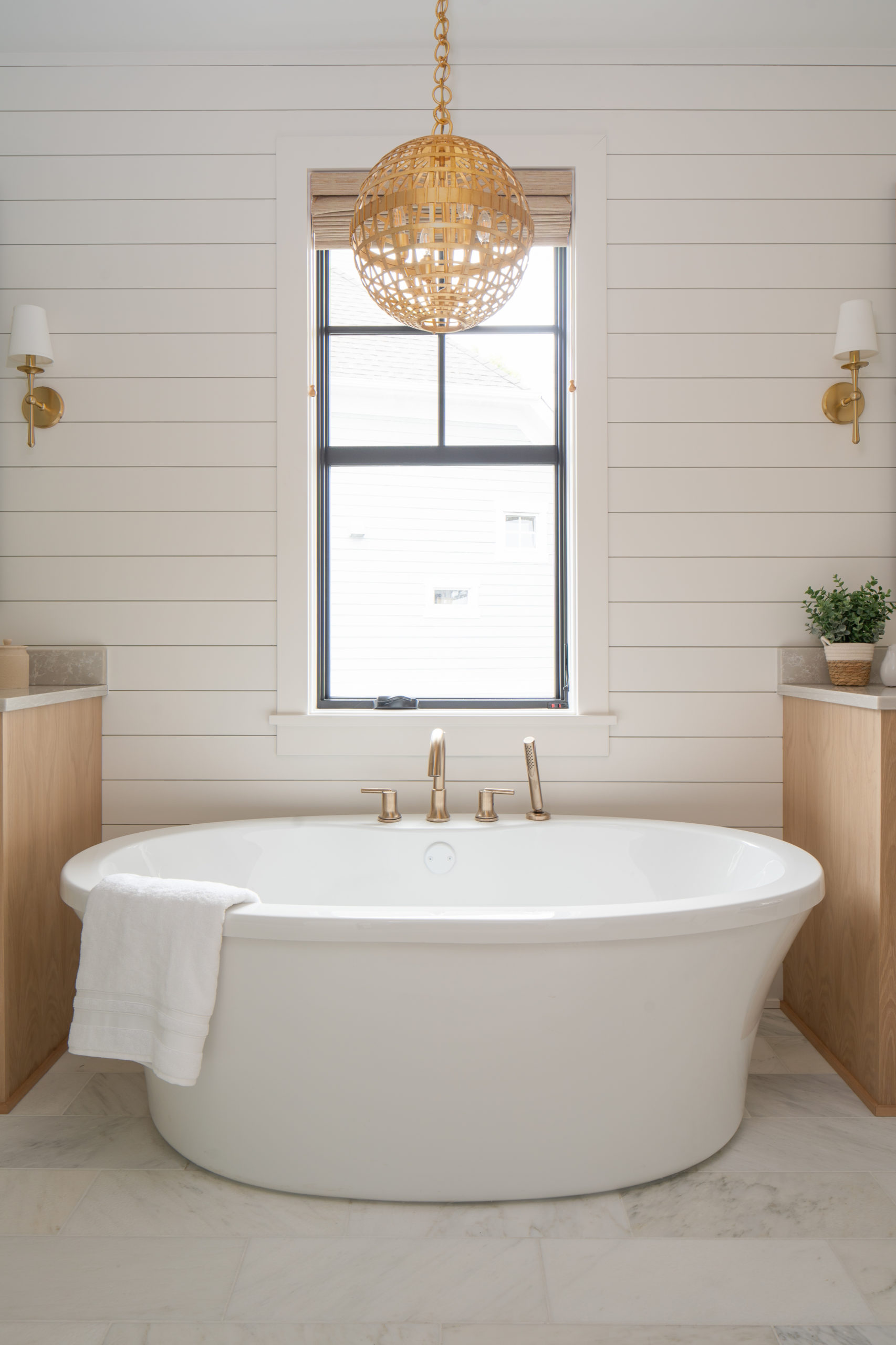 The Lake Escape custom home remodel features a luxurious white bathroom with a large tub and a mesmerizing chandelier.