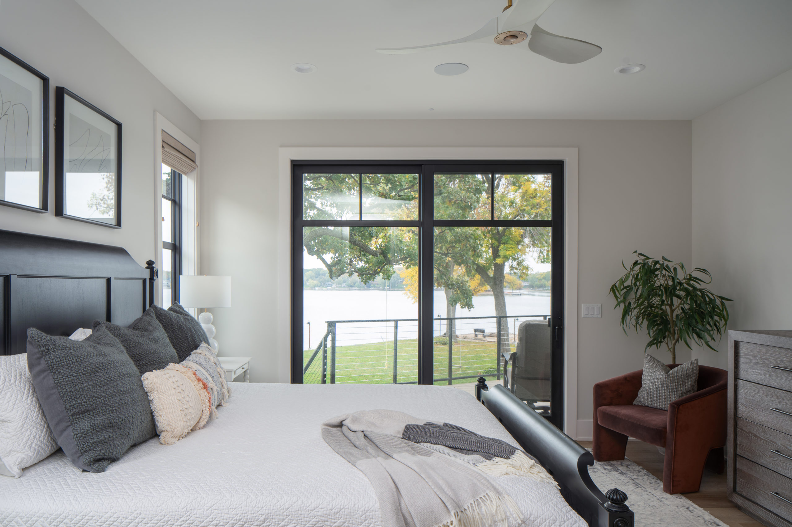 The Lake Escape custom home remodel transformed a bedroom into a serene oasis, complete with a comfortable bed, spacious dresser, and a luxurious sliding glass door.