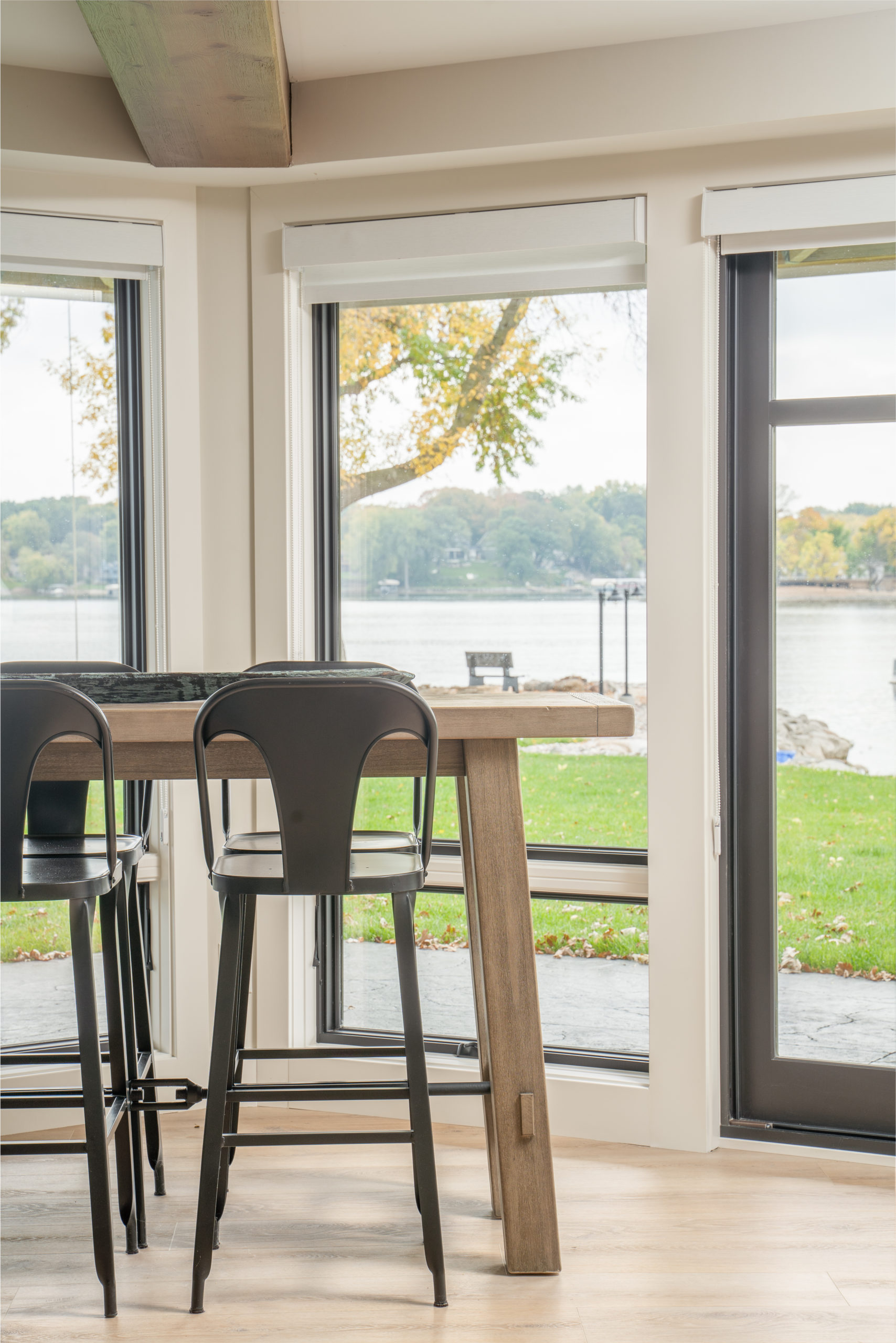 The Lake Escape custom home remodel features a dining room with large windows overlooking a lake.