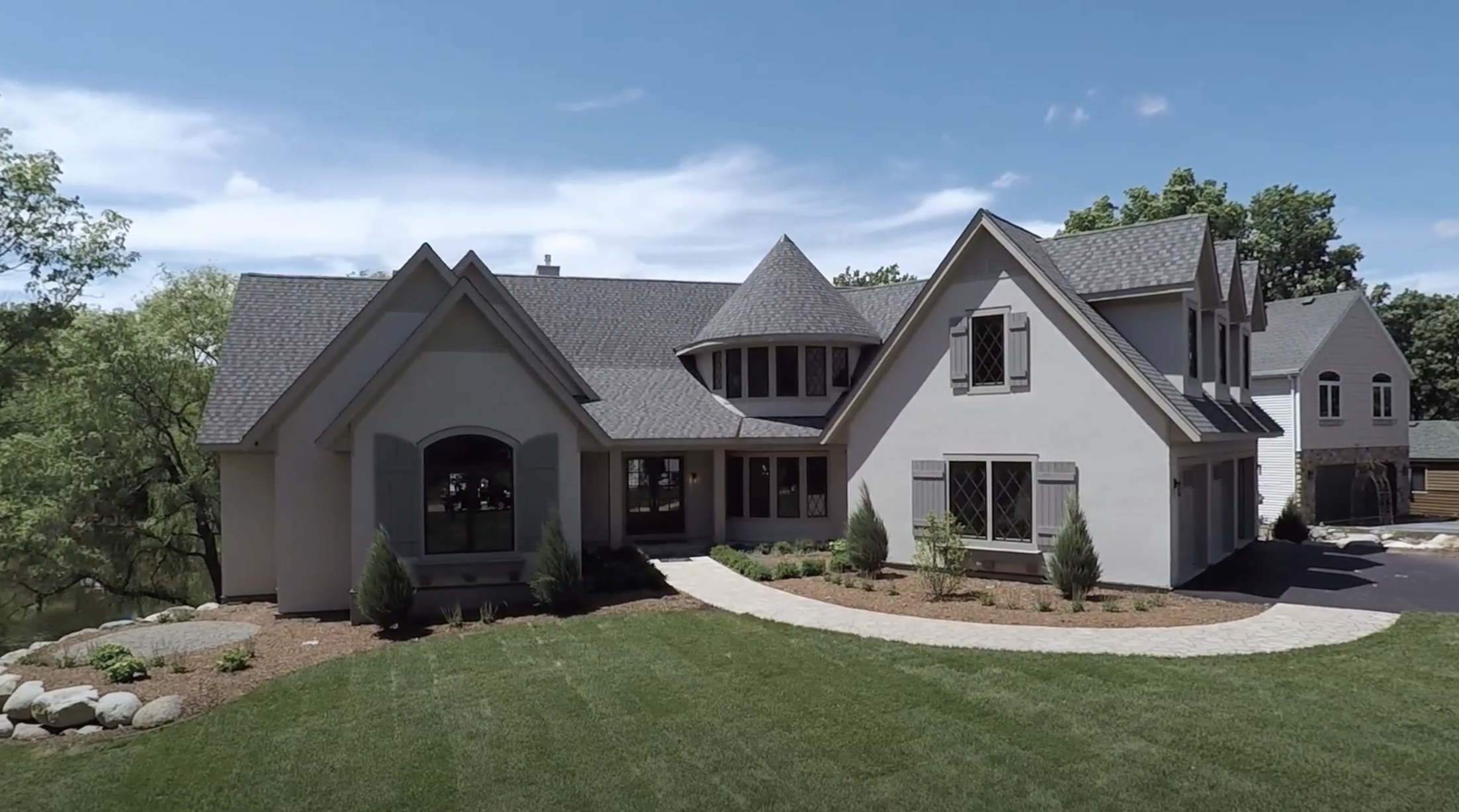 A custom home build video series showcasing a 3D rendering of a home with a large front yard.