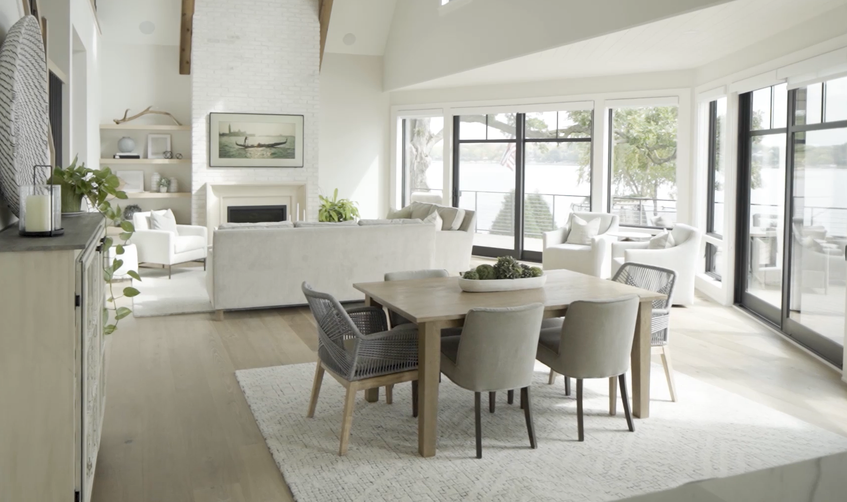 The Lake Escape custom home remodel features a white living room and dining room with large windows.