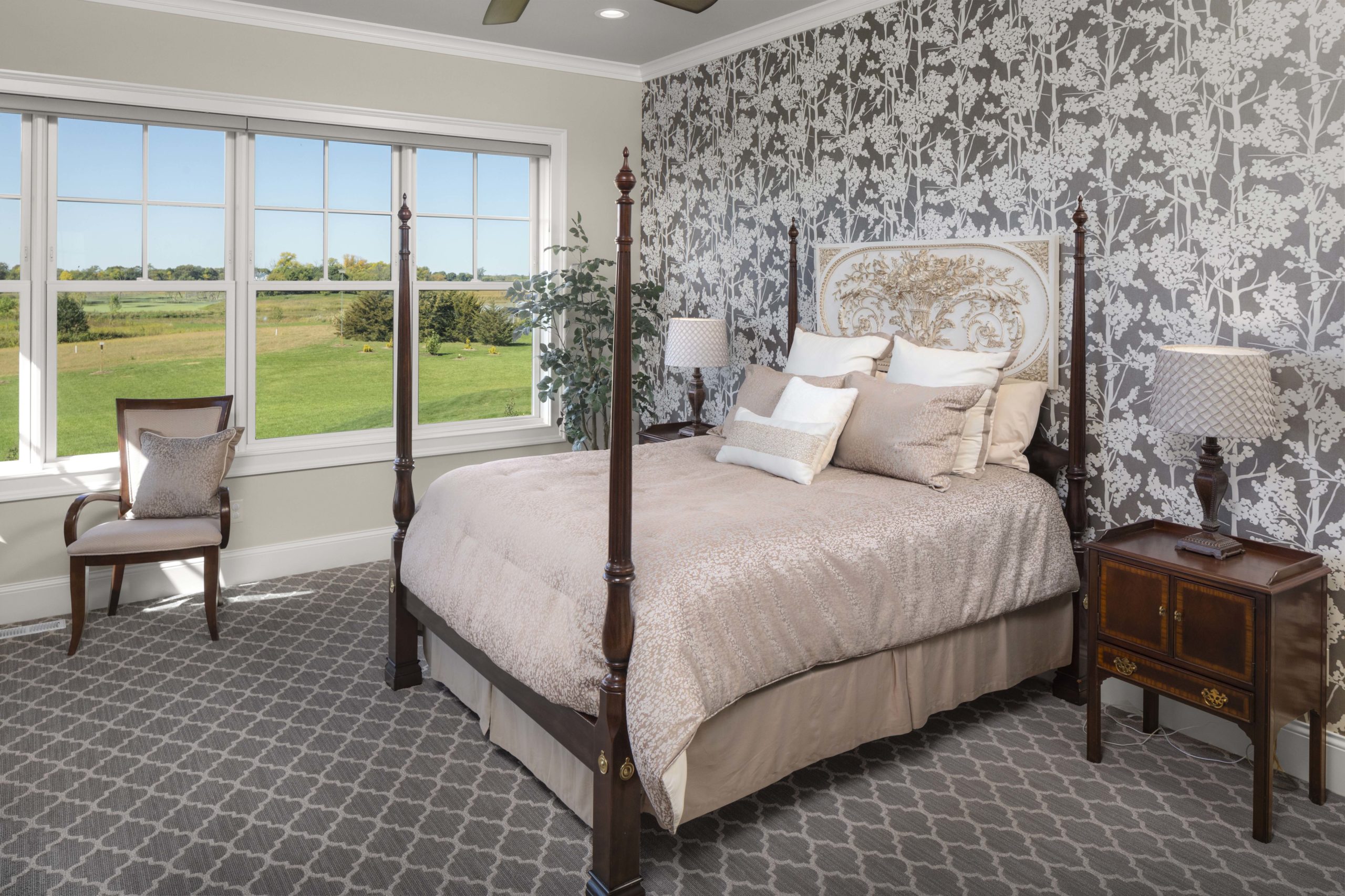 A prairie custom home bedroom with a bed and a window overlooking a golf course.