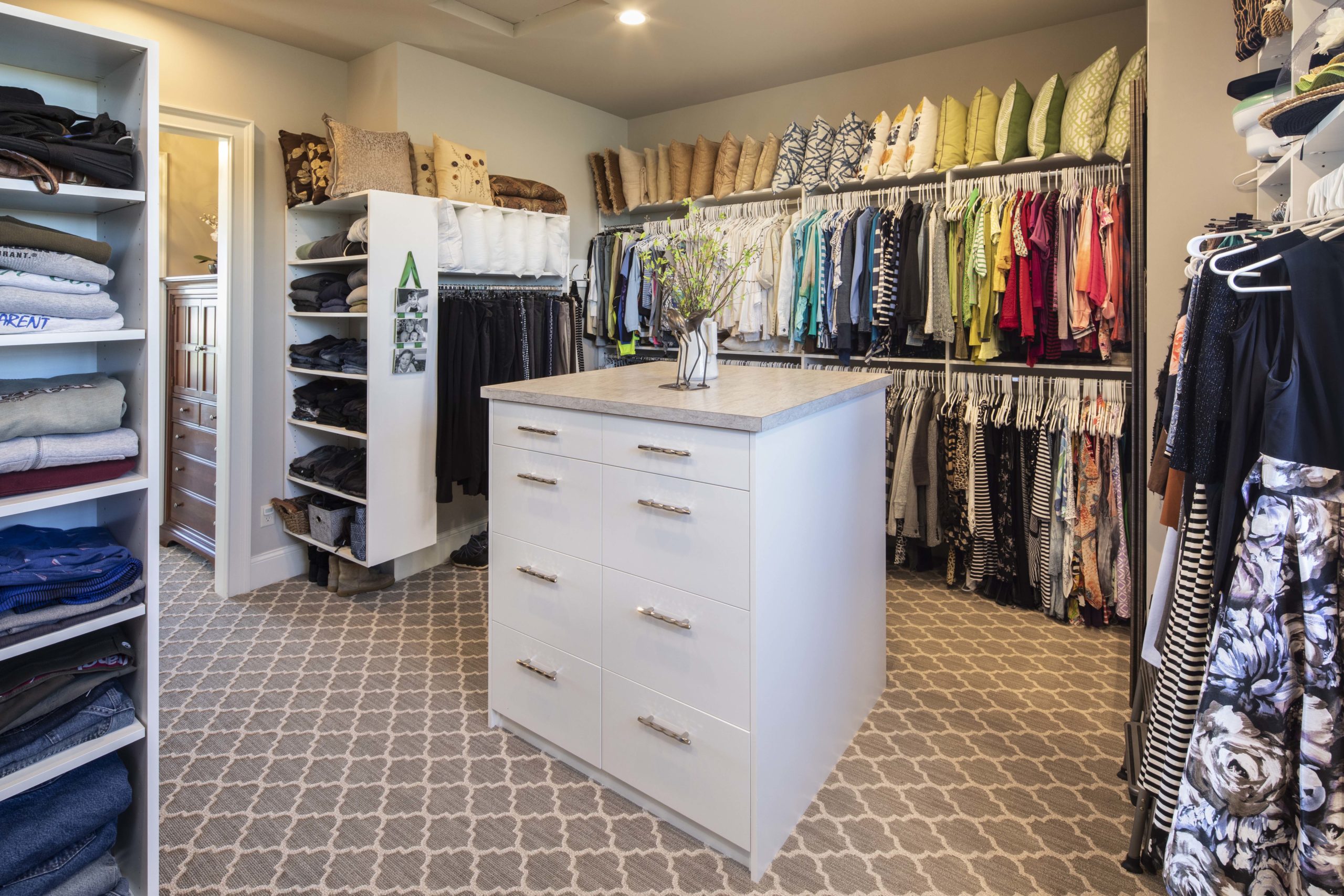 A prairie transitional walk in closet with lots of clothes and drawers.