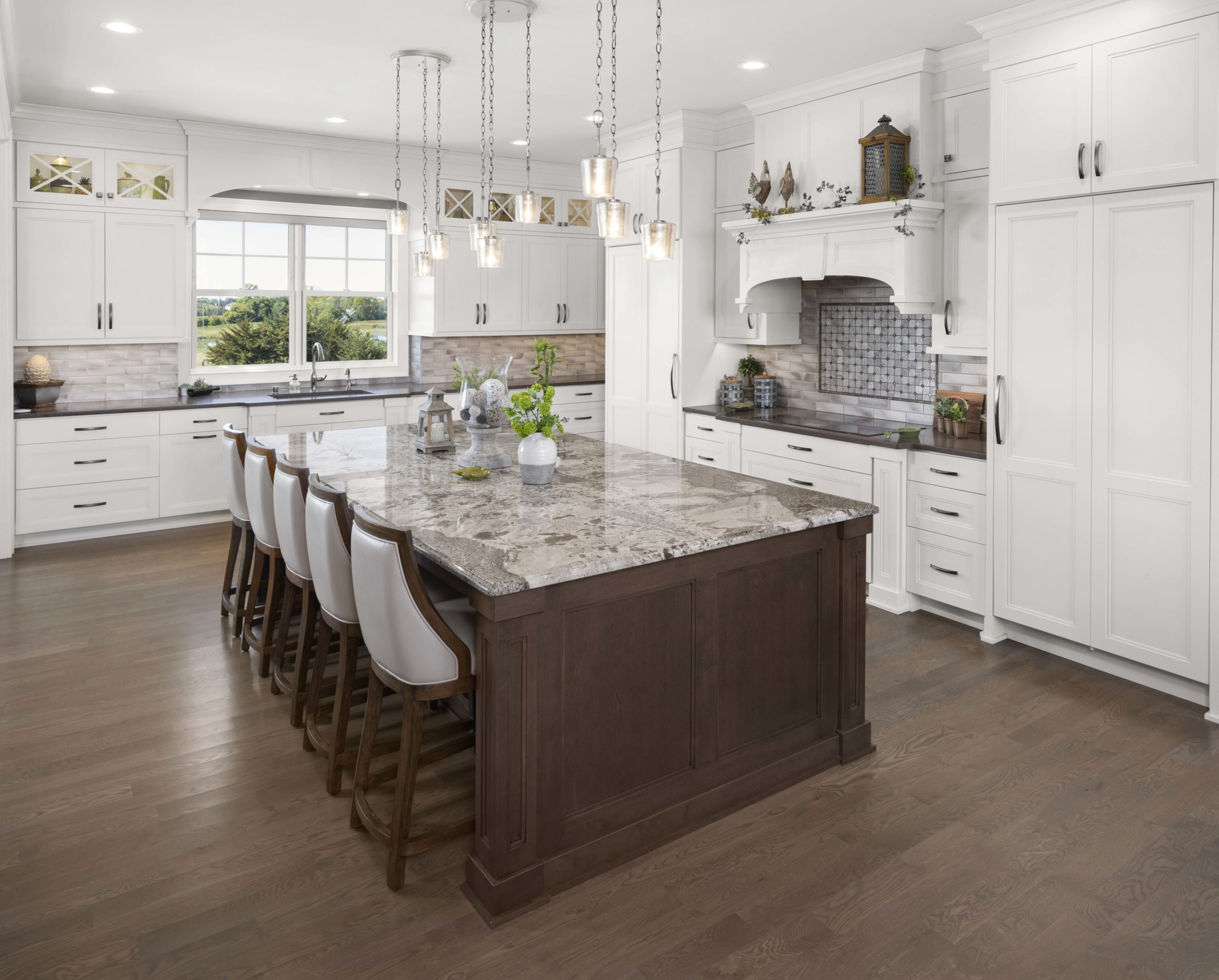 A prairie transitional custom home with a large kitchen featuring white cabinets and a center island.