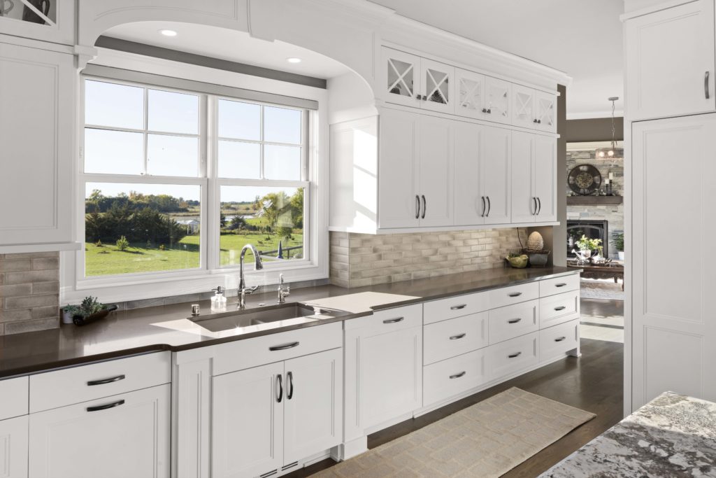 A prairie kitchen with white cabinets and granite counter tops.