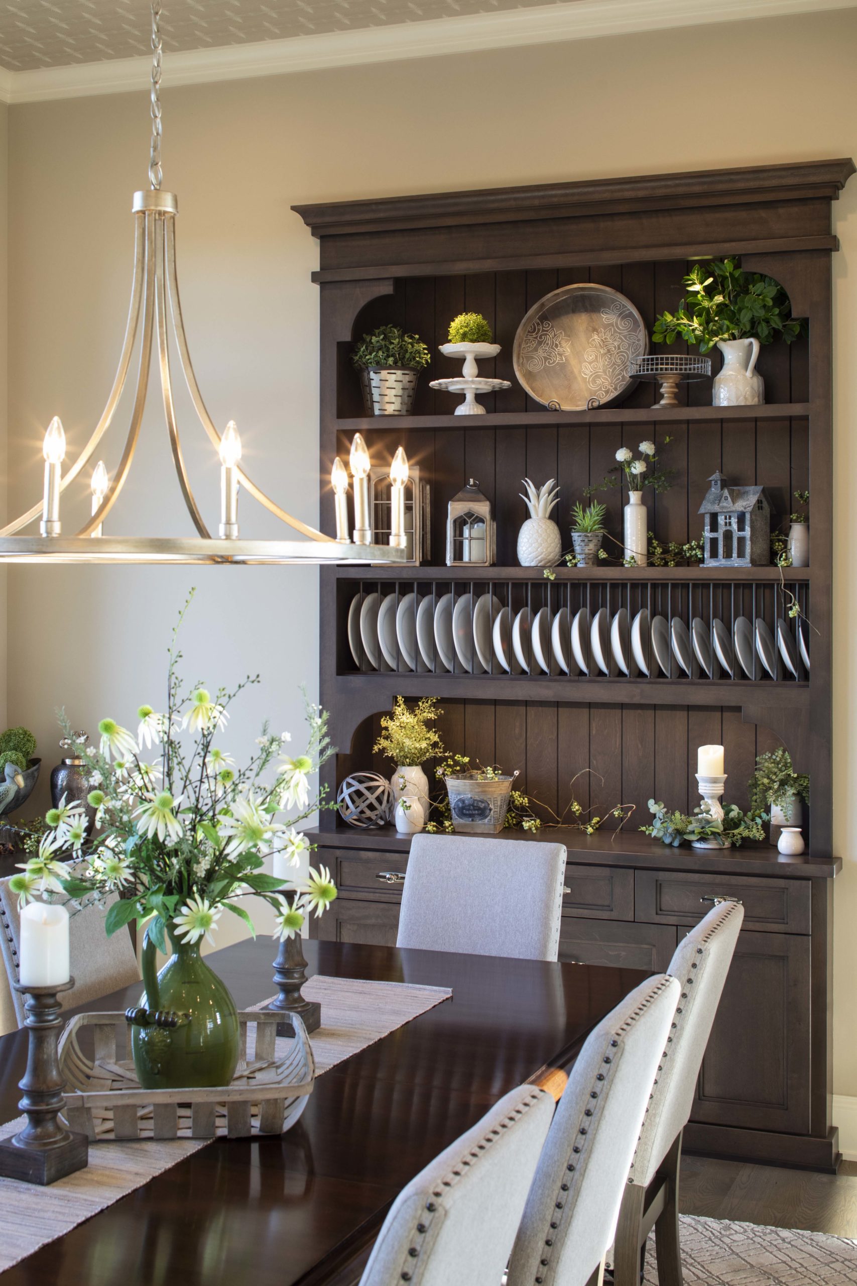 A prairie-style dining room with a custom table, chairs, and a stunning chandelier.