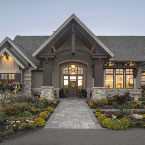 A beautiful prairie transitional home with a stone driveway and custom landscaping.