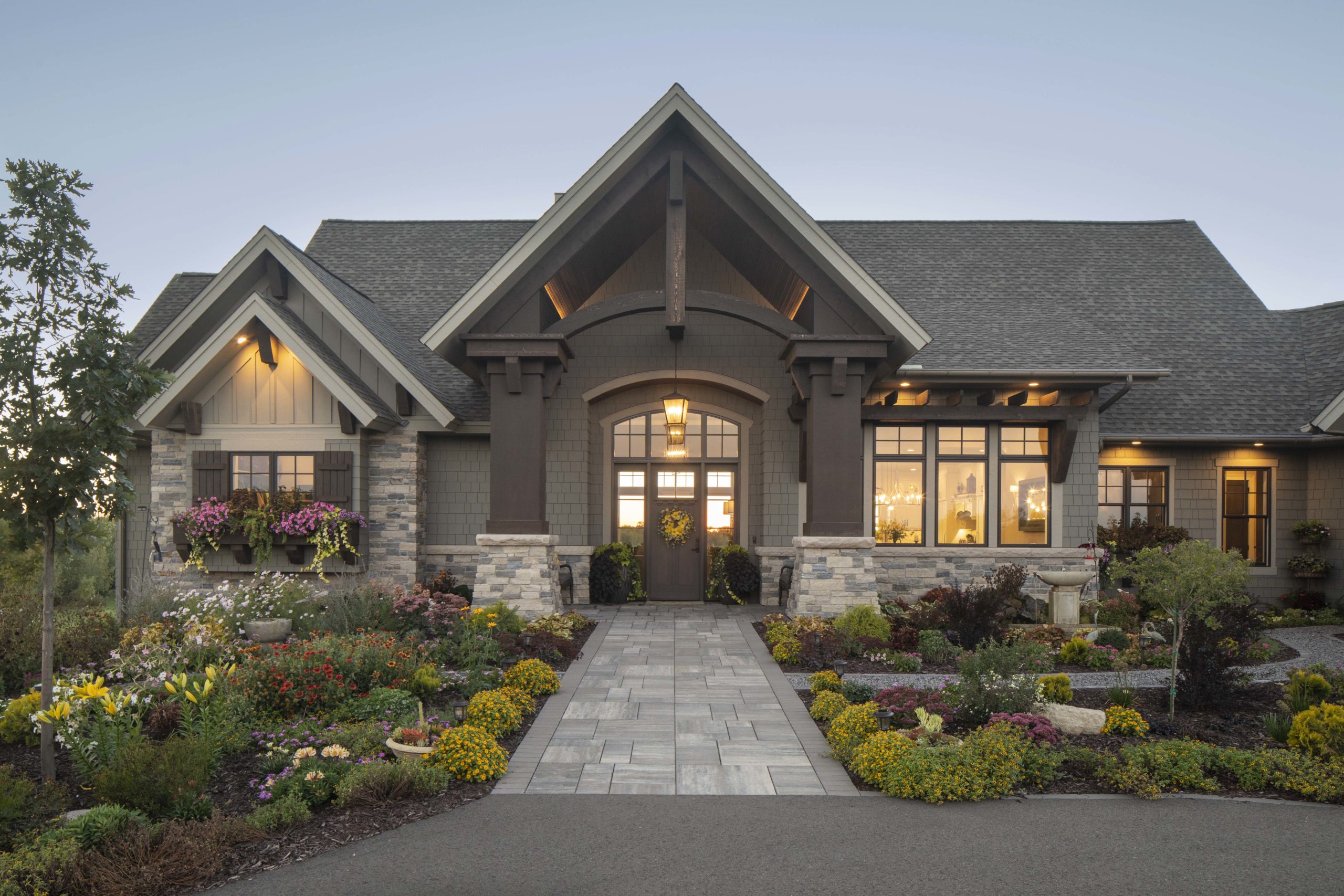 A beautiful prairie transitional home with a stone driveway and custom landscaping.