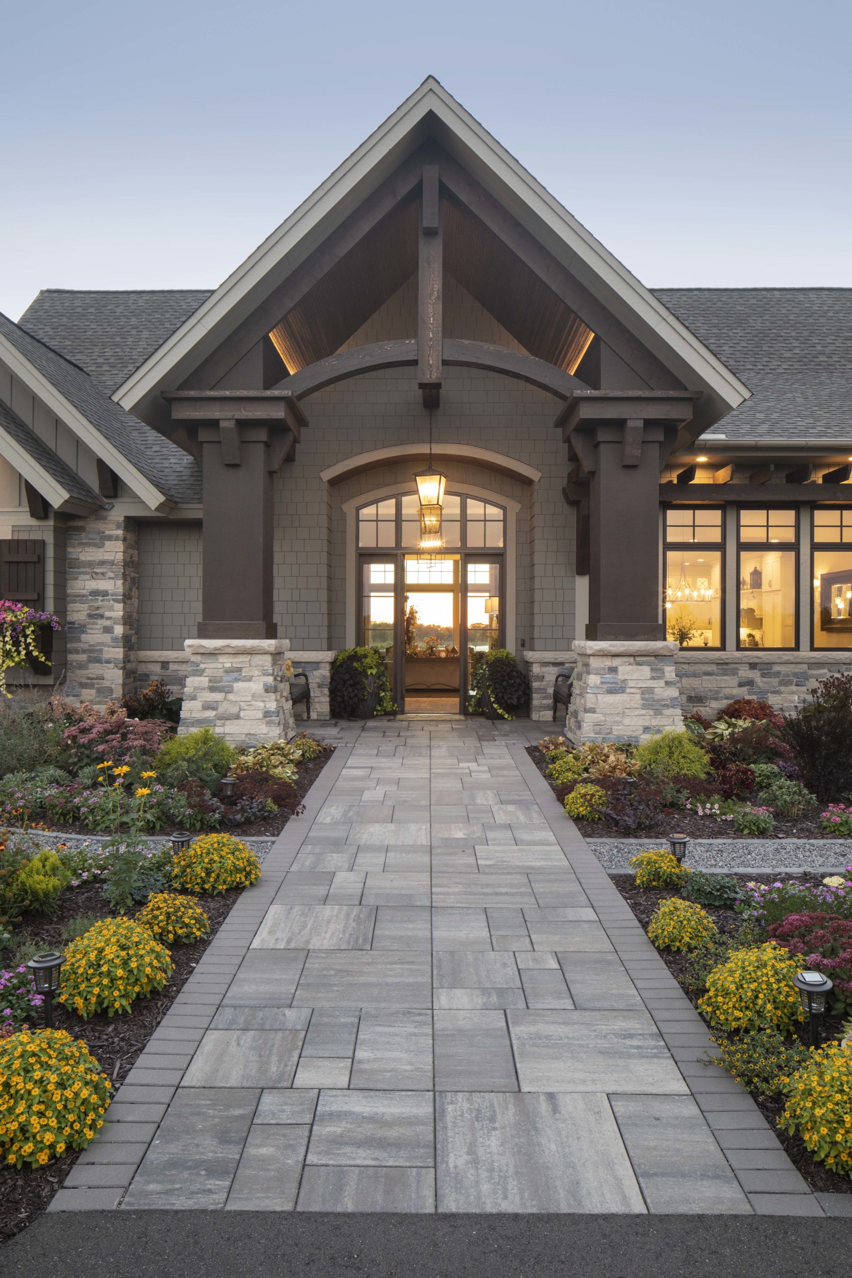 The entrance to a prairie transitional custom home with a walkway and landscaping.
