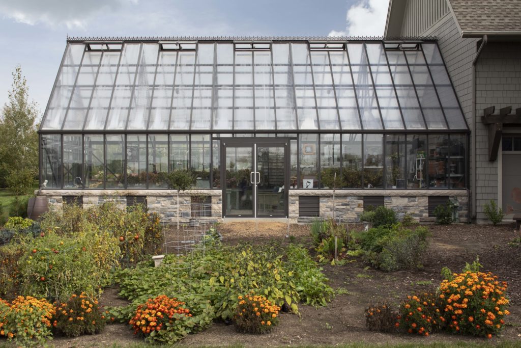 A large custom greenhouse in a garden.