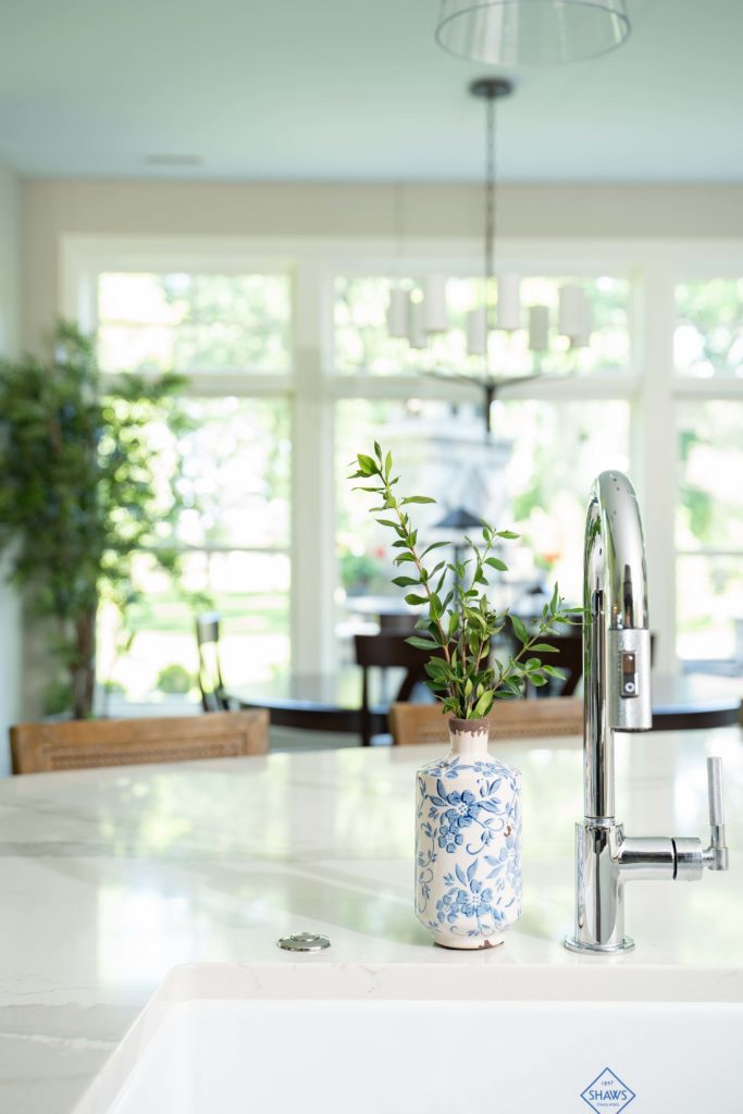 A white sink in a kitchen with a plant in it, featured in The Lake Escape custom home remodel.