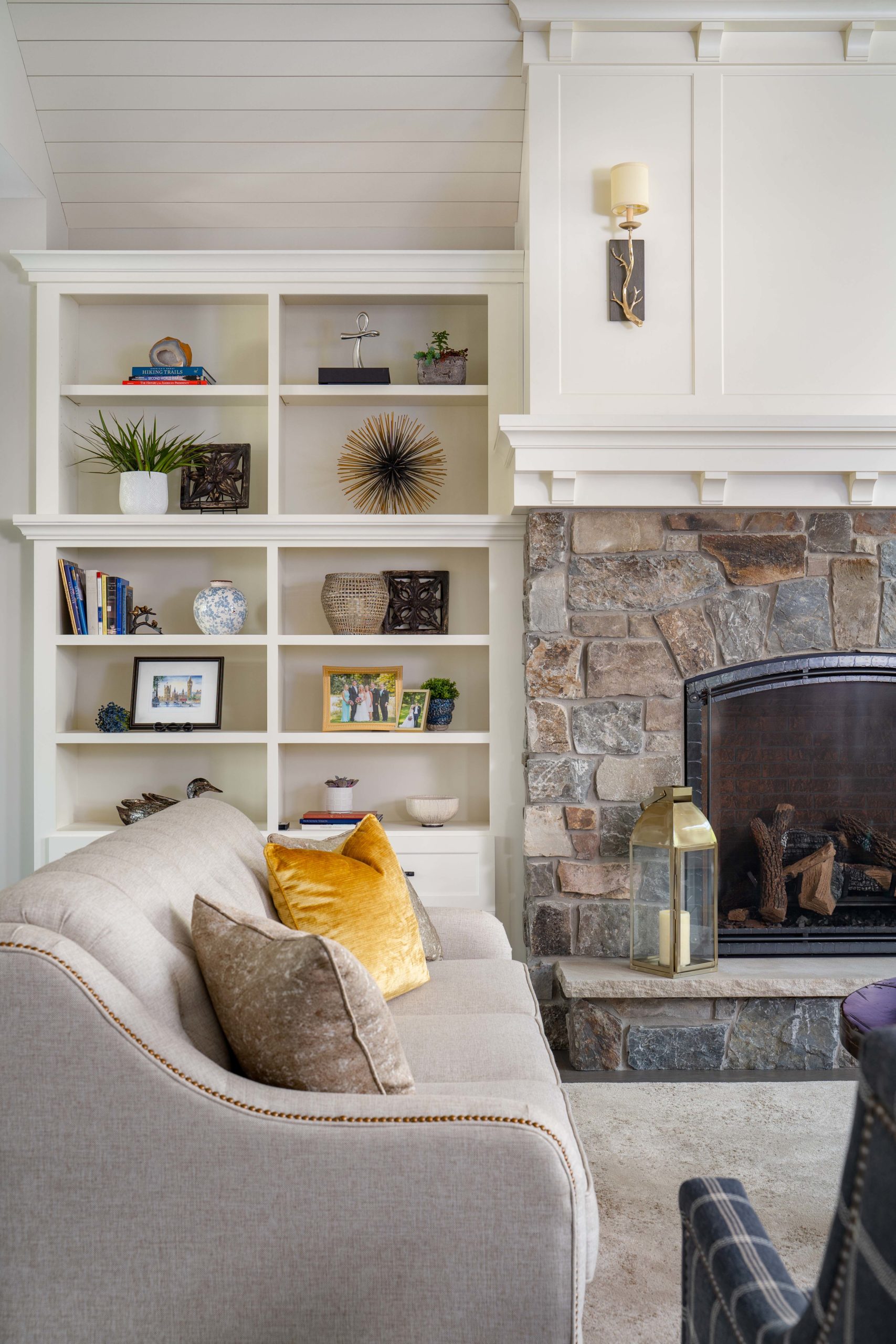 The Lake Escape custom home remodel transformed a living room with a fireplace and bookshelves into a cozy retreat.
