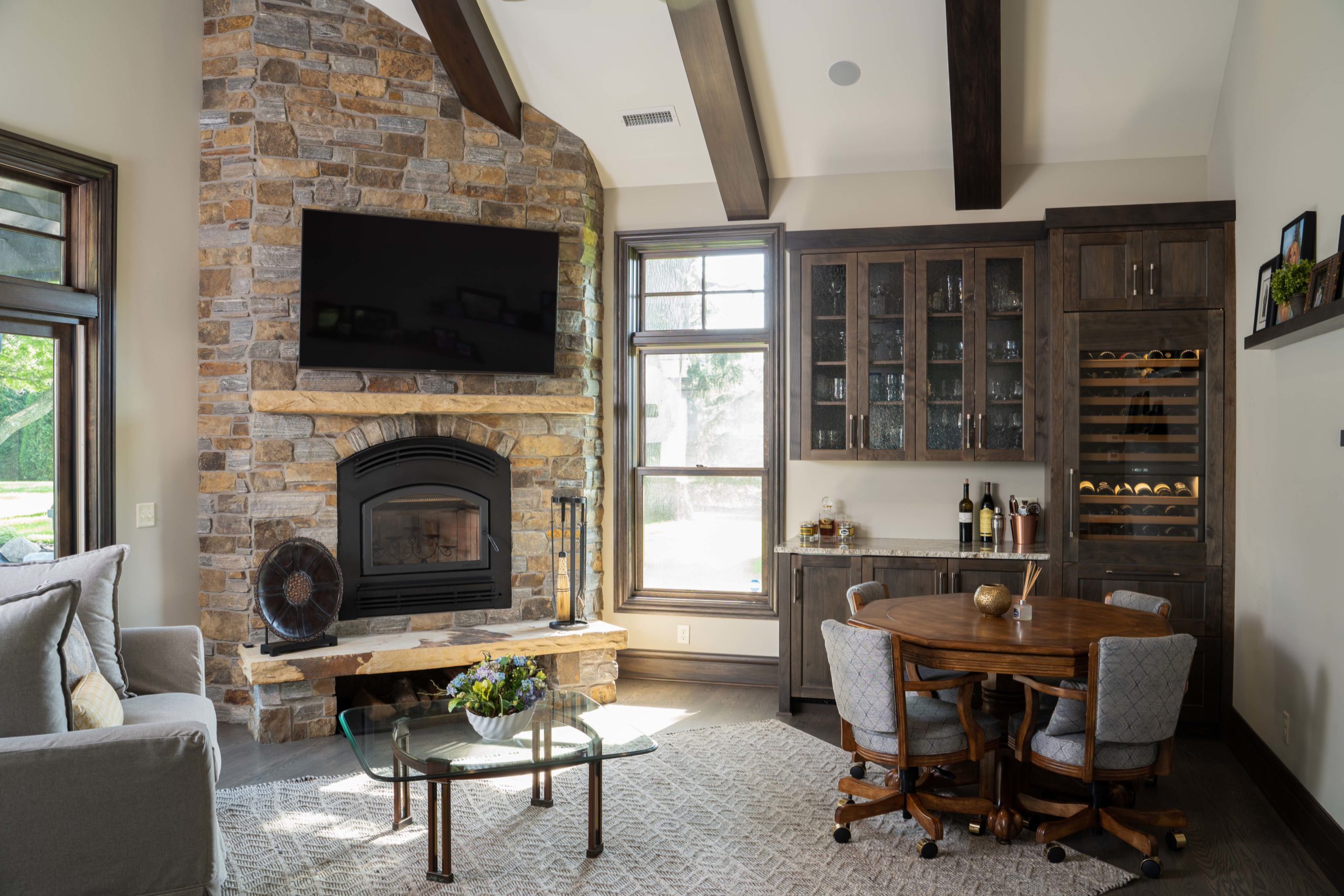 The Lake Escape custom home remodel features a living room with a stone fireplace and TV.