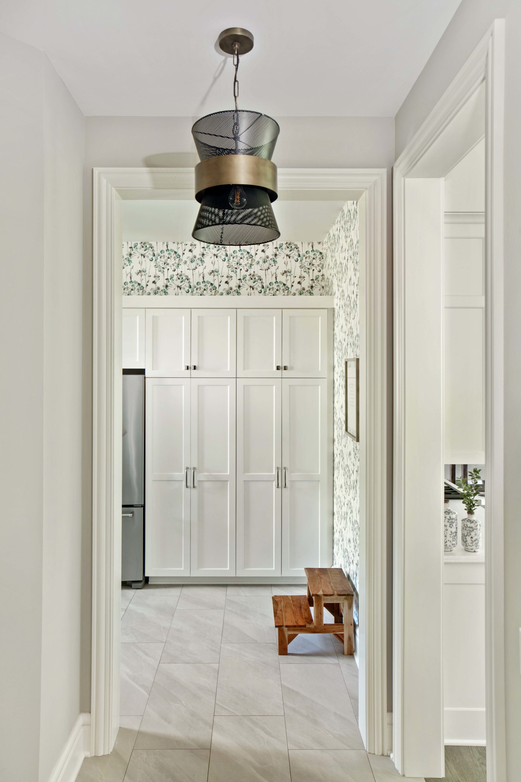 The Lake Escape custom home remodel showcases a hallway with white cabinets and a stylish light fixture.