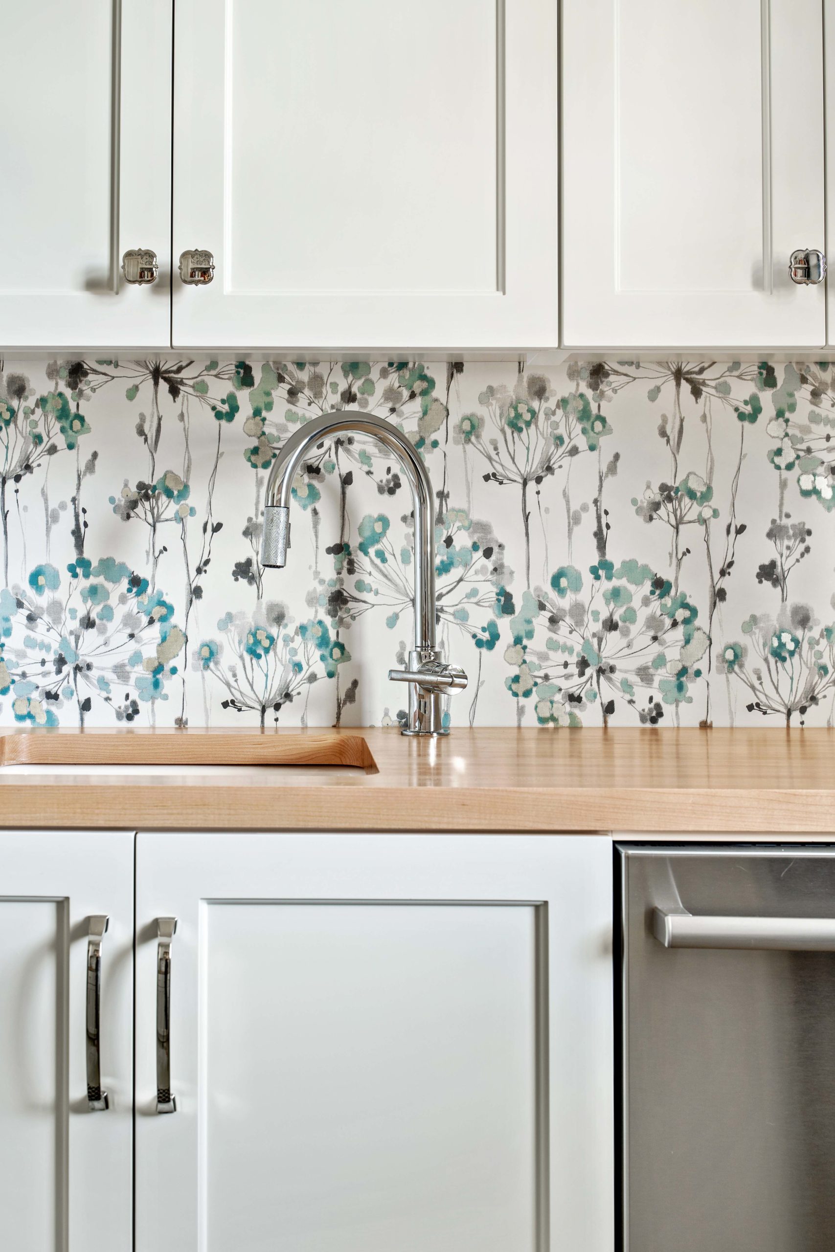 The Lake Escape custom home remodel features a white kitchen with a floral backsplash.