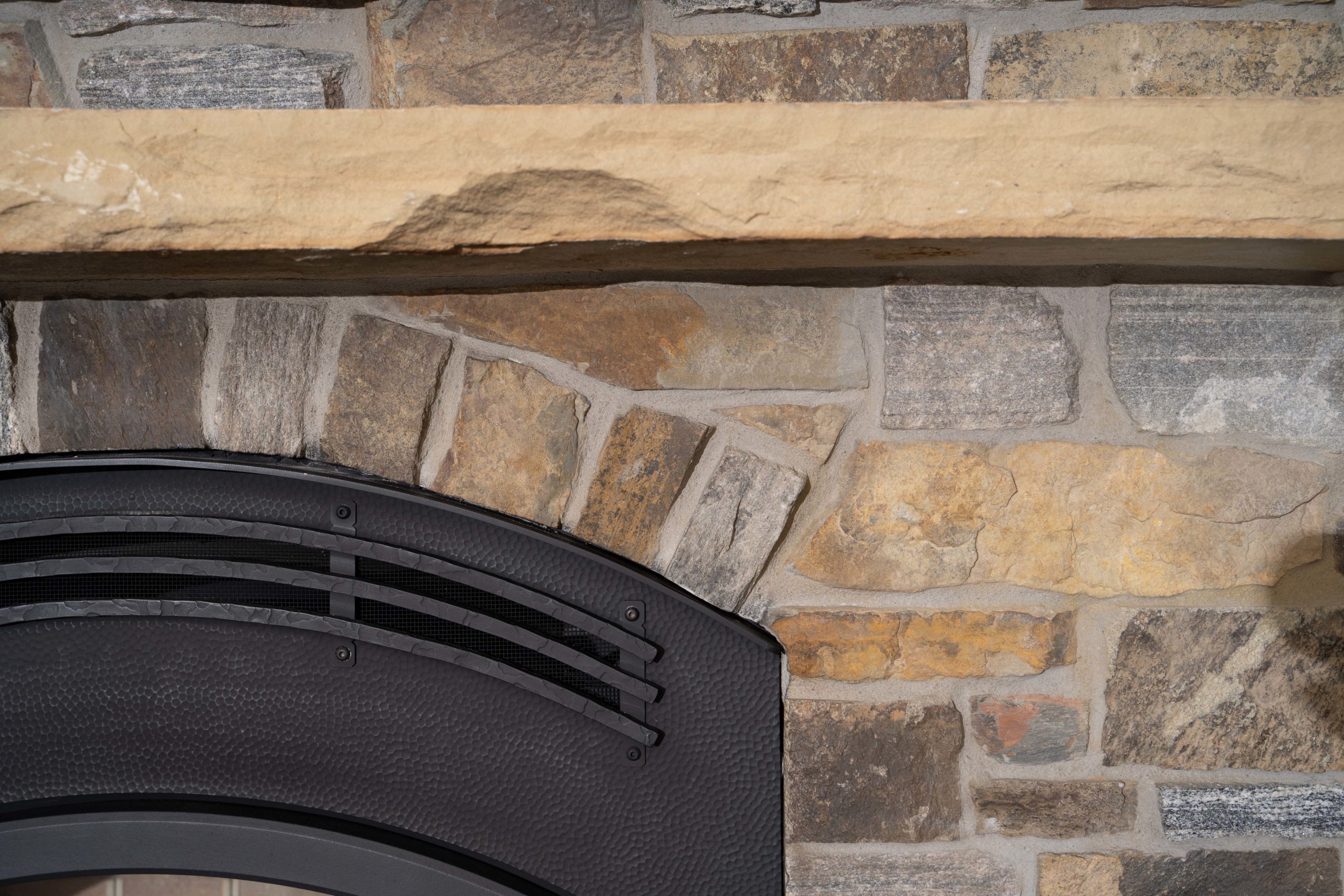 A close up of a stone fireplace with a mantle in The Lake Escape custom home remodel.