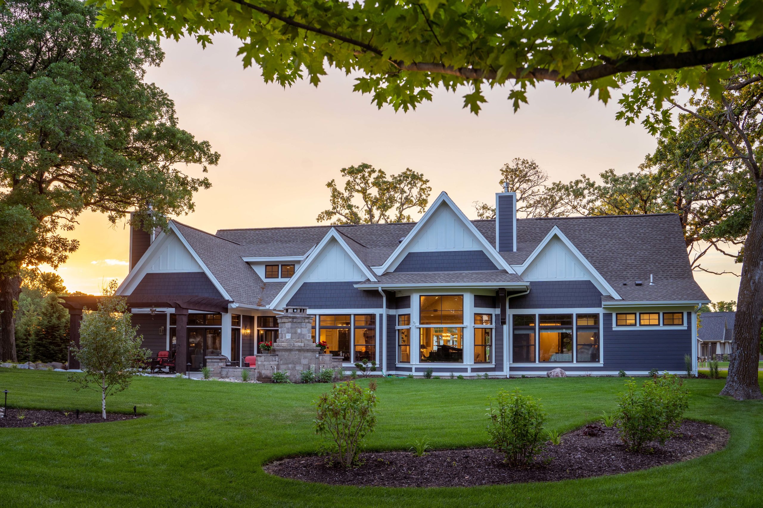 The Lake Escape custom home remodel featuring a large lawn and trees at dusk.