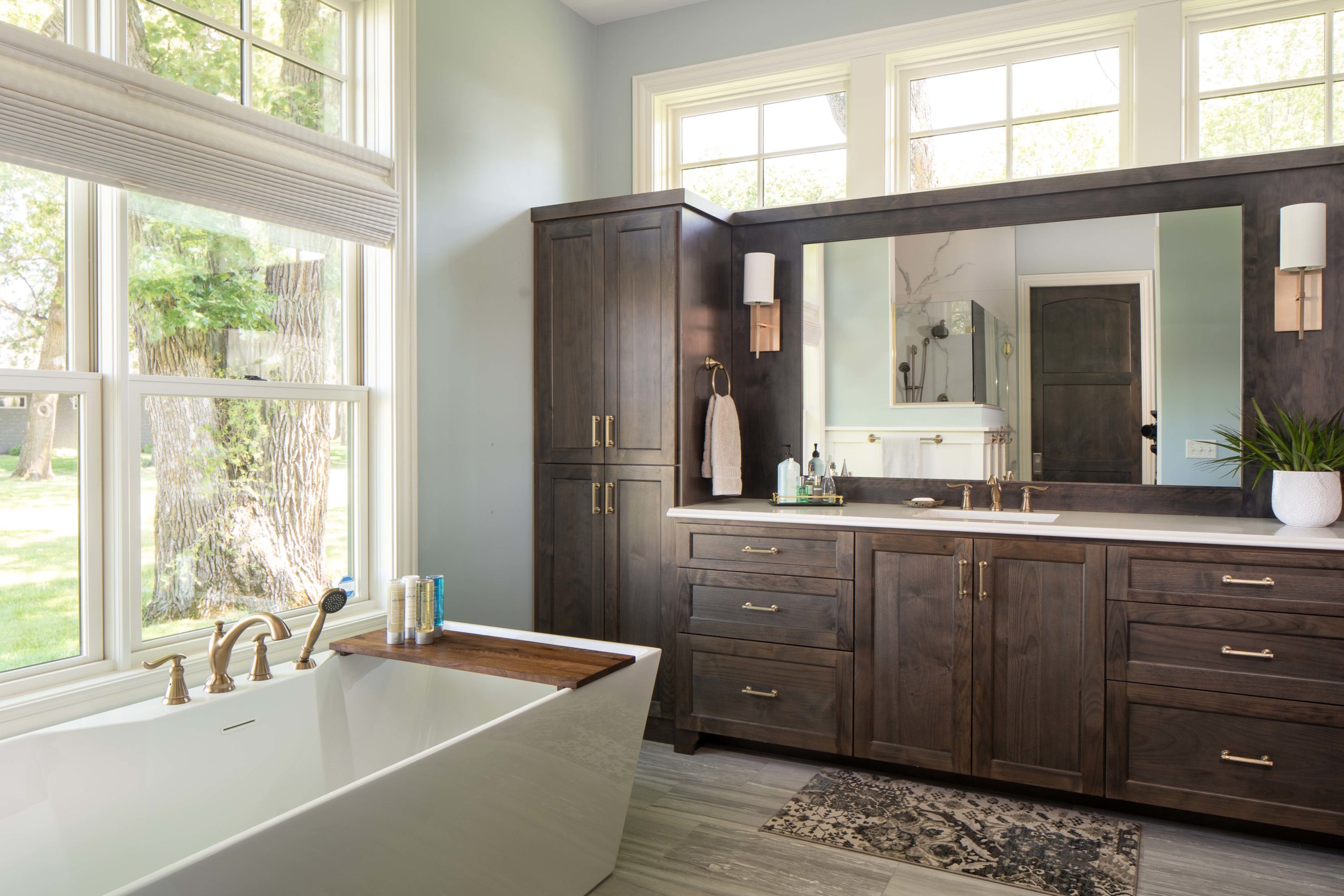 The Lake Escape custom home remodel showcases a bathroom with elegant wooden cabinets and a luxurious tub.