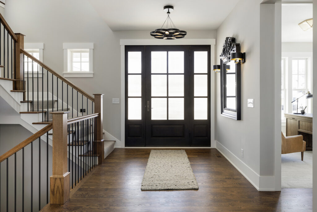 A hallway with a black door and hardwood floors.