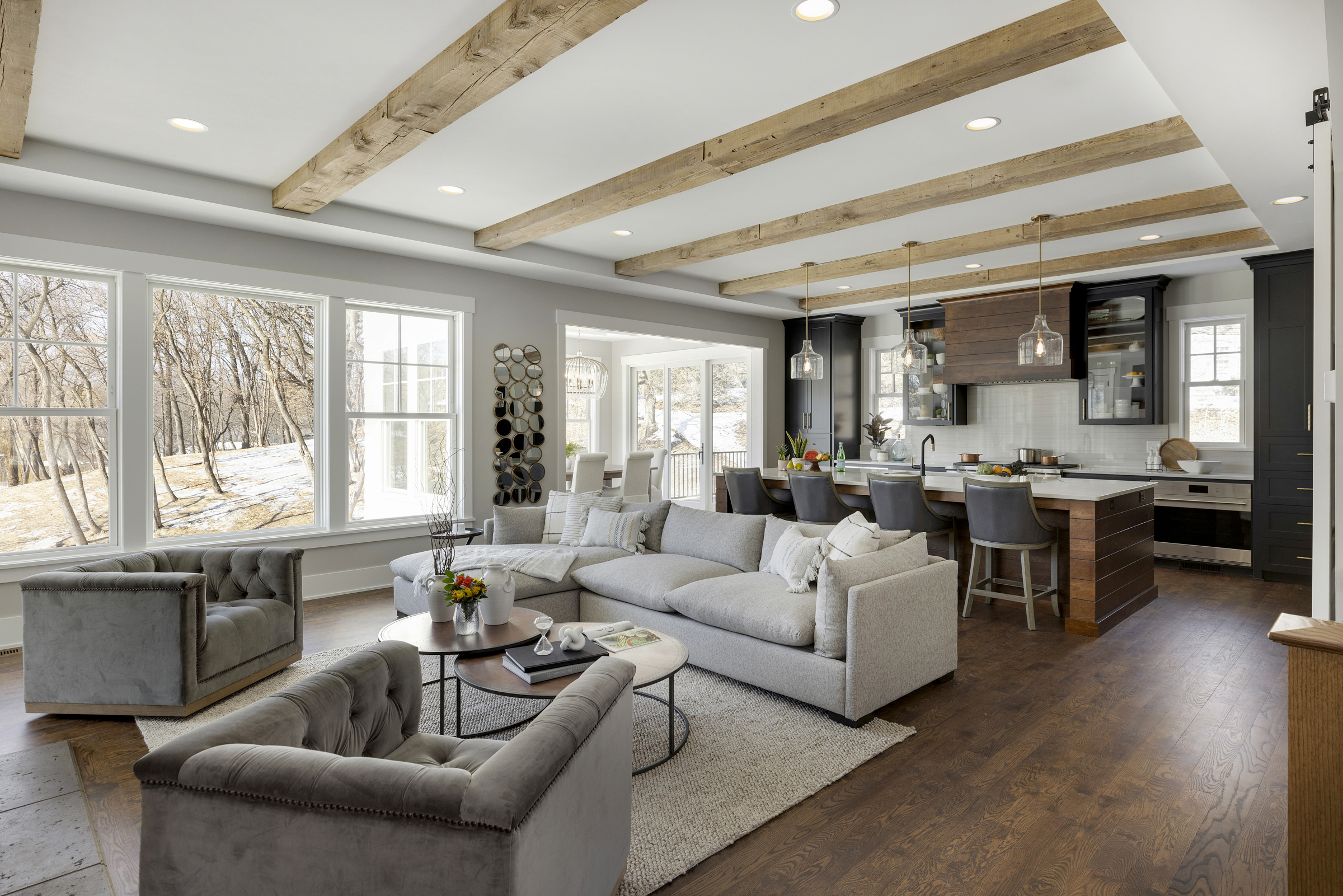 A living room with wood beams and gray furniture.
