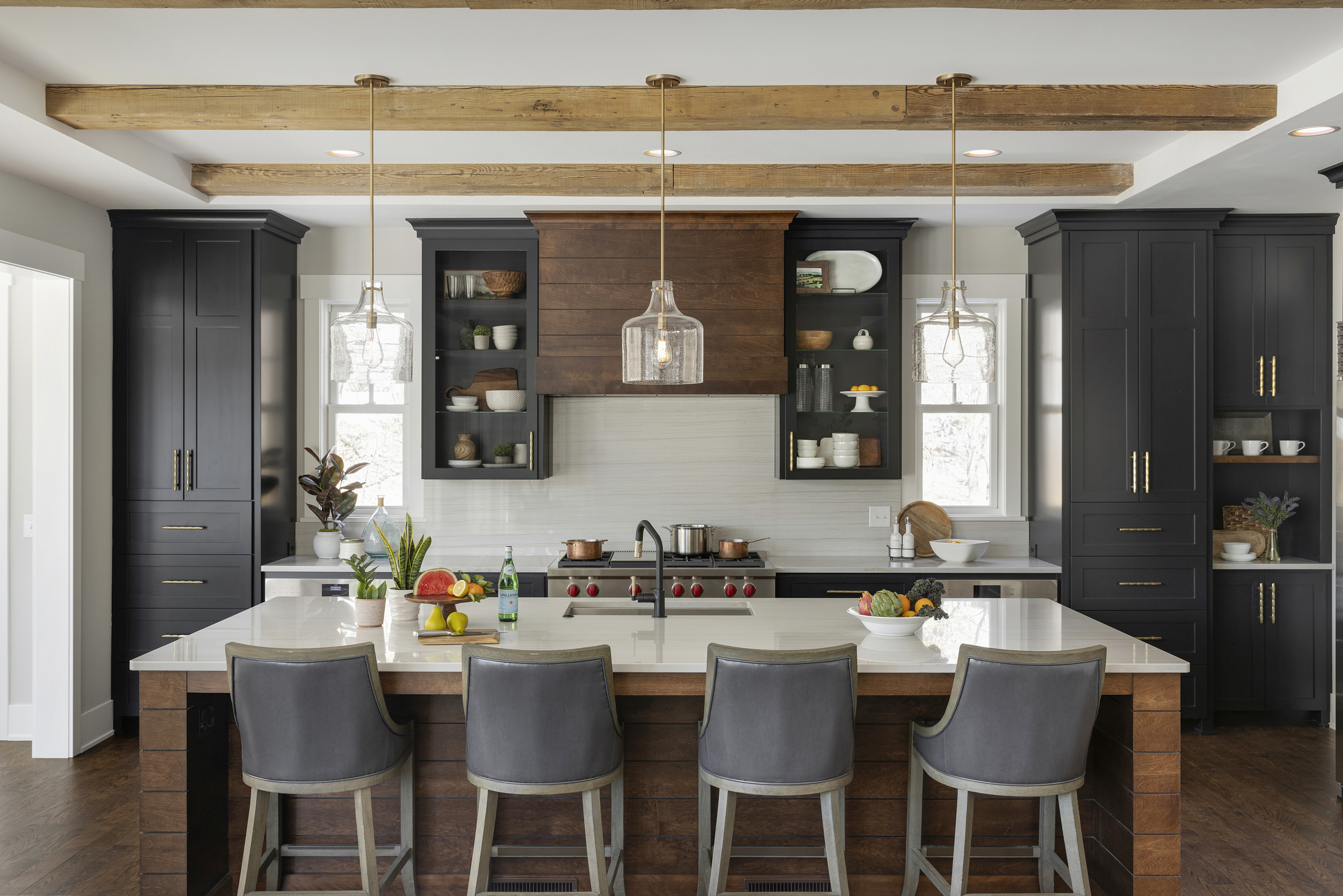 A kitchen with black cabinets and wooden beams.