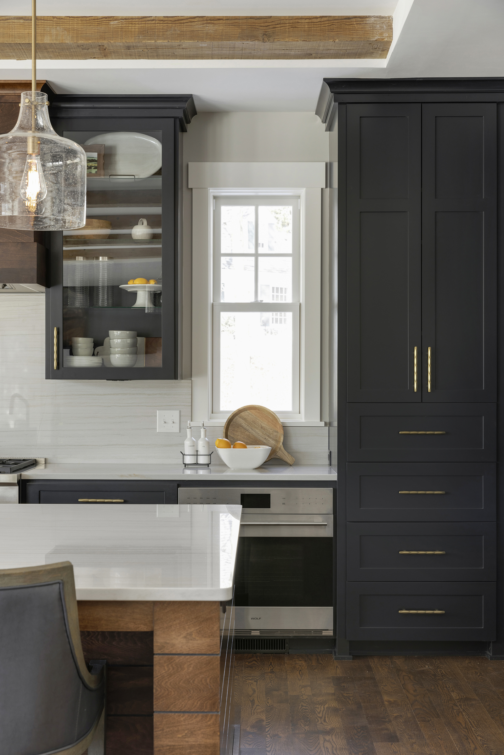 A kitchen with black cabinets and wood floors.
