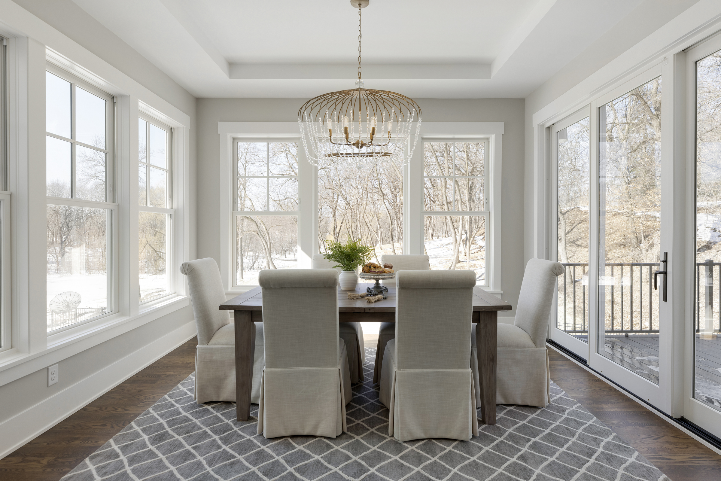 A dining room with white walls and a gray rug.