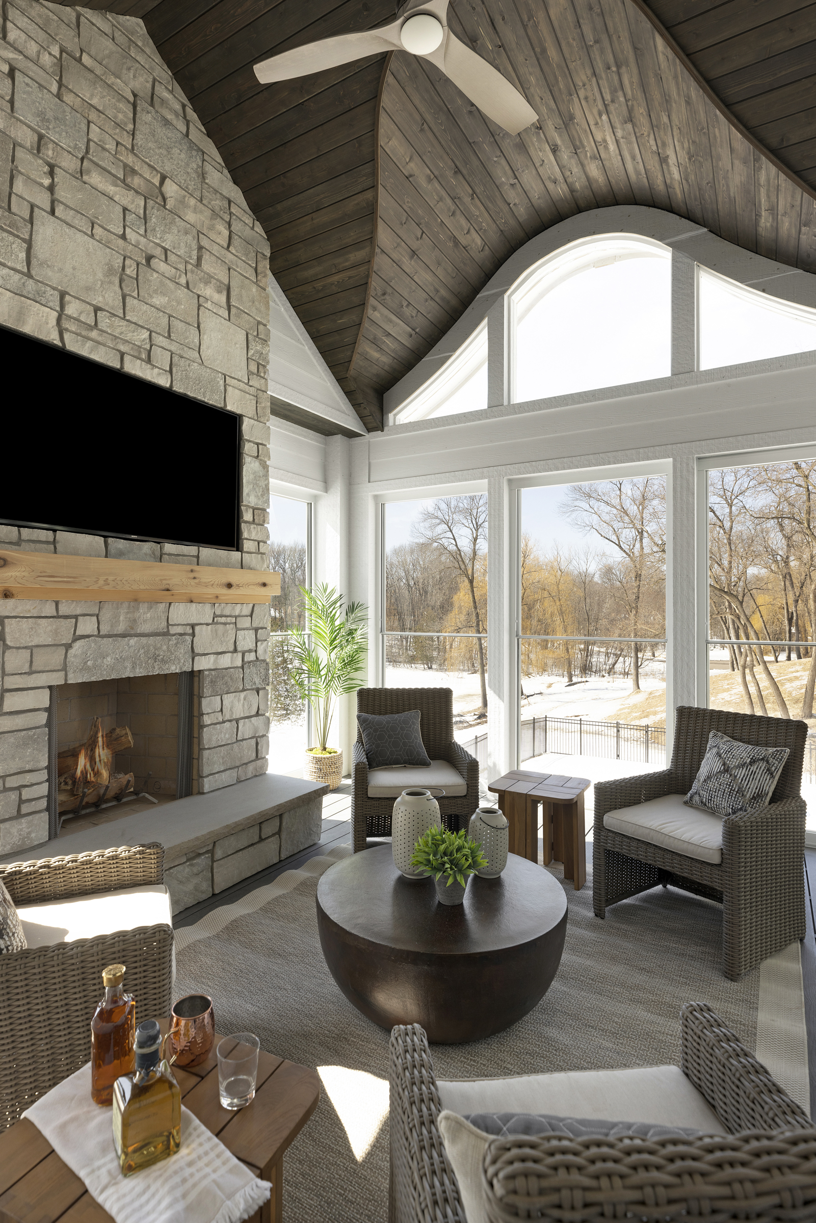 A living room with a stone fireplace and a flat screen tv.