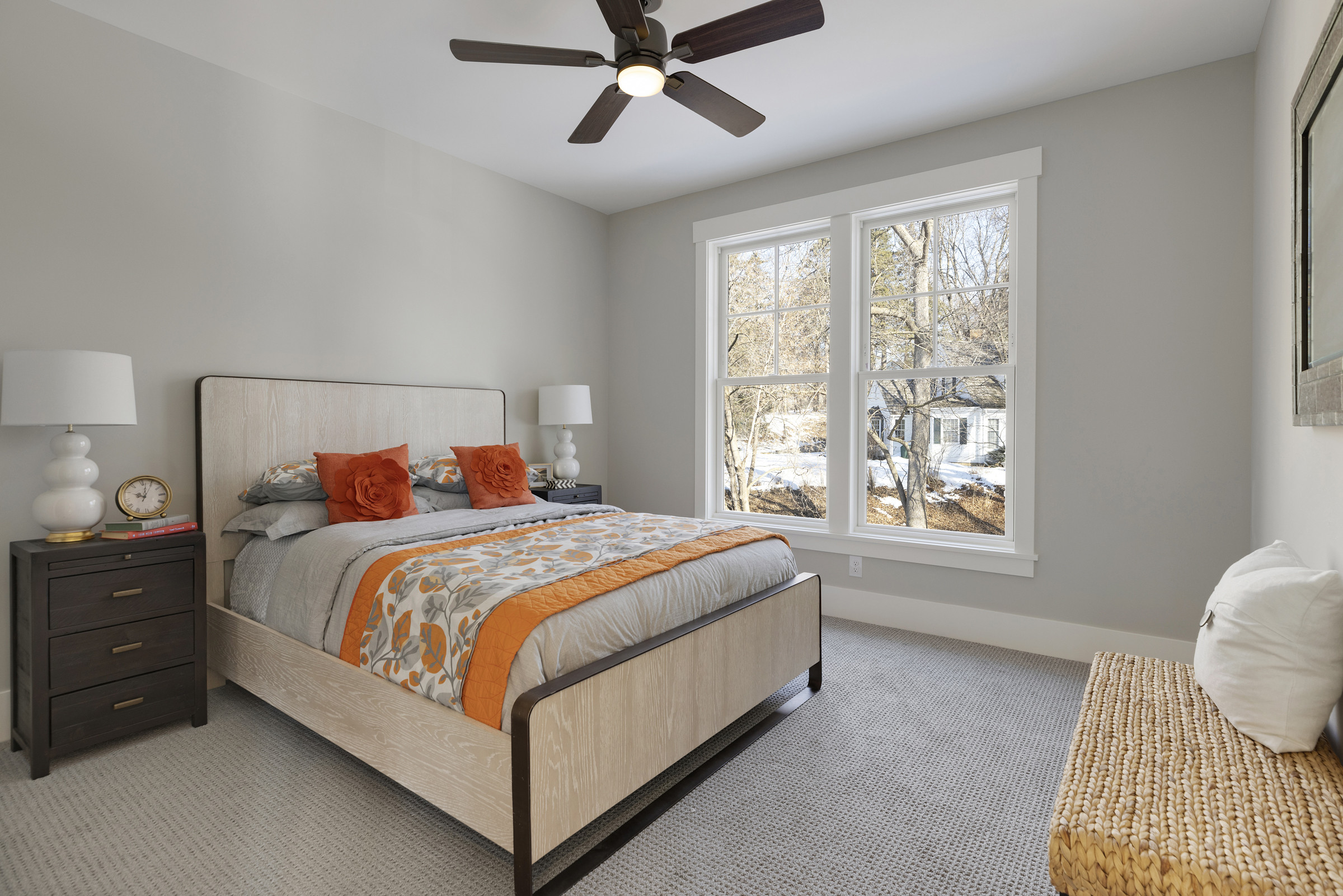 A bedroom with a gray bed and orange accents.