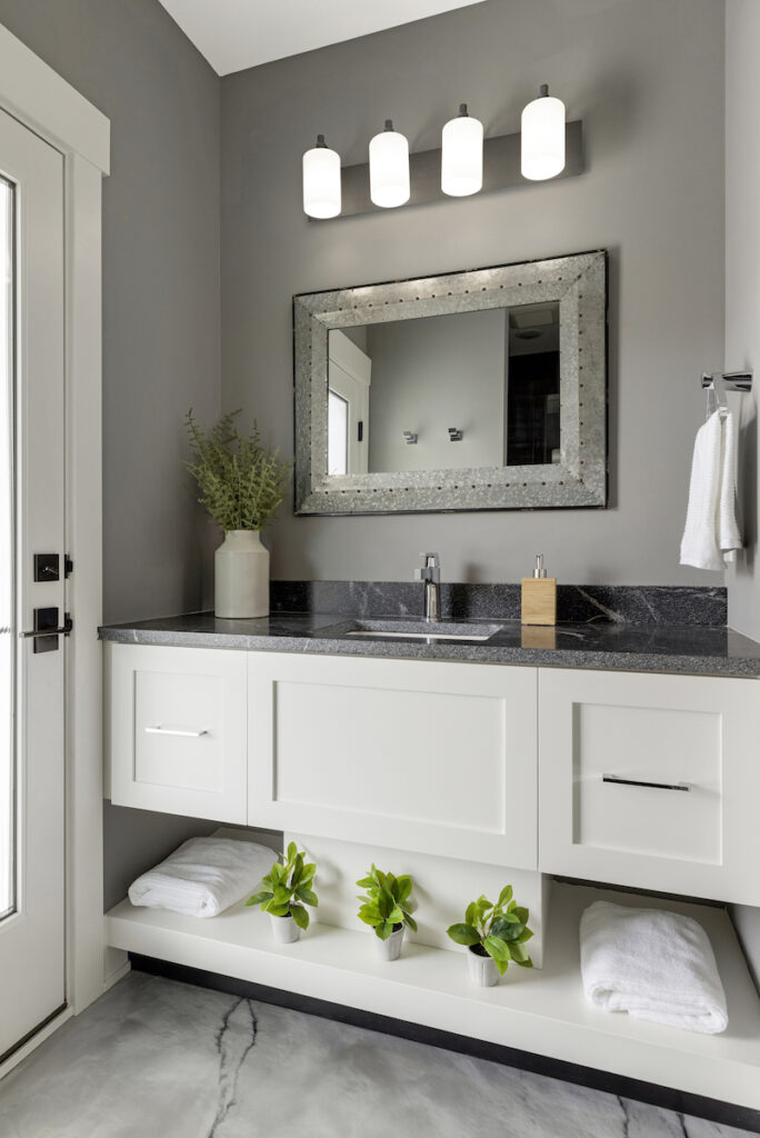 A modern bathroom with white cabinets and a door.