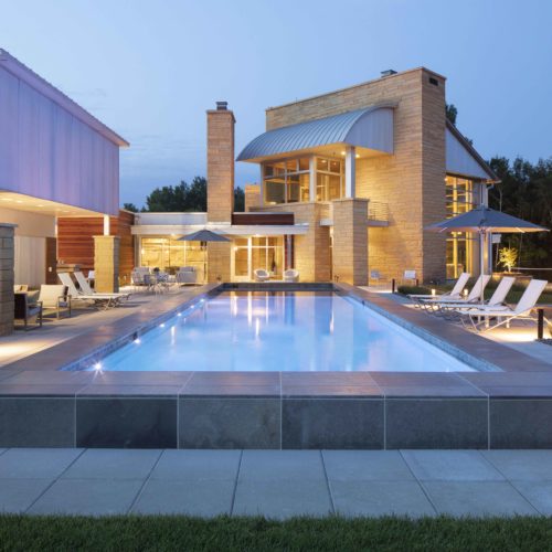 A modern home with a swimming pool at dusk.