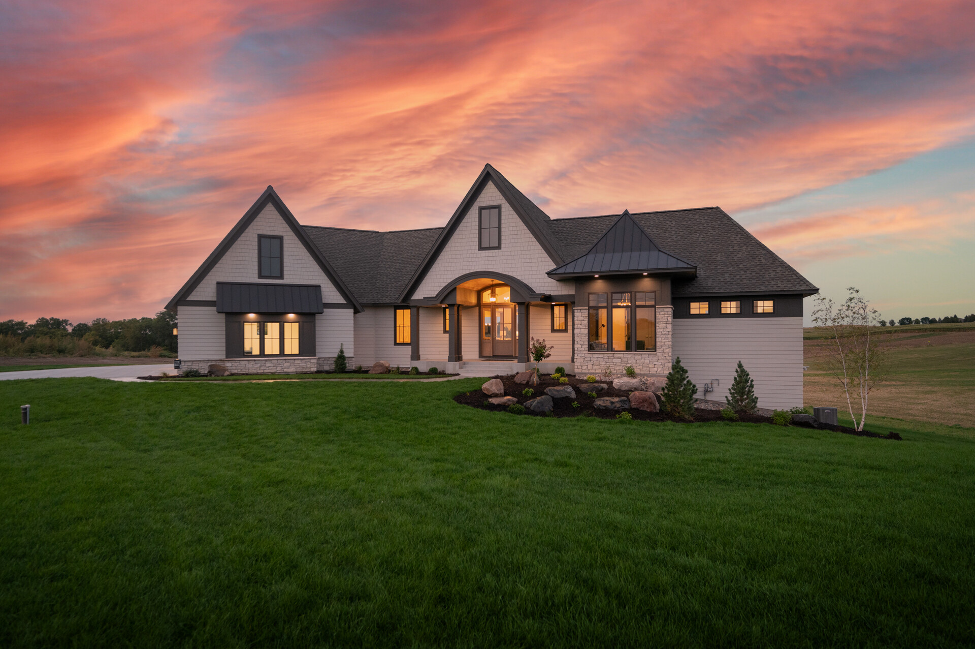 A beautiful custom home with a sunset sky behind it.